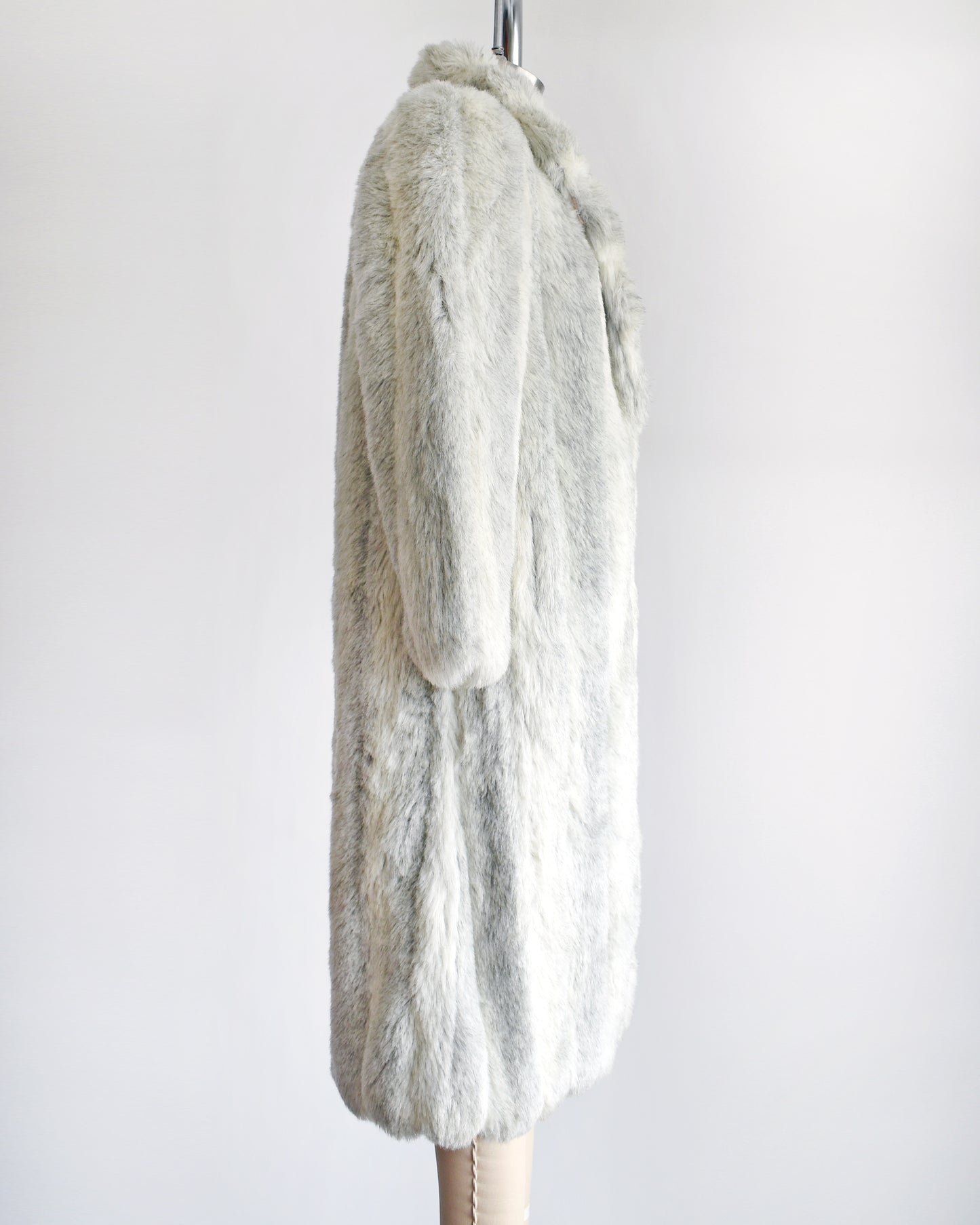 Side view of a vintage 1980s  cream colored faux fur coat with light and dark gray stripes. 
