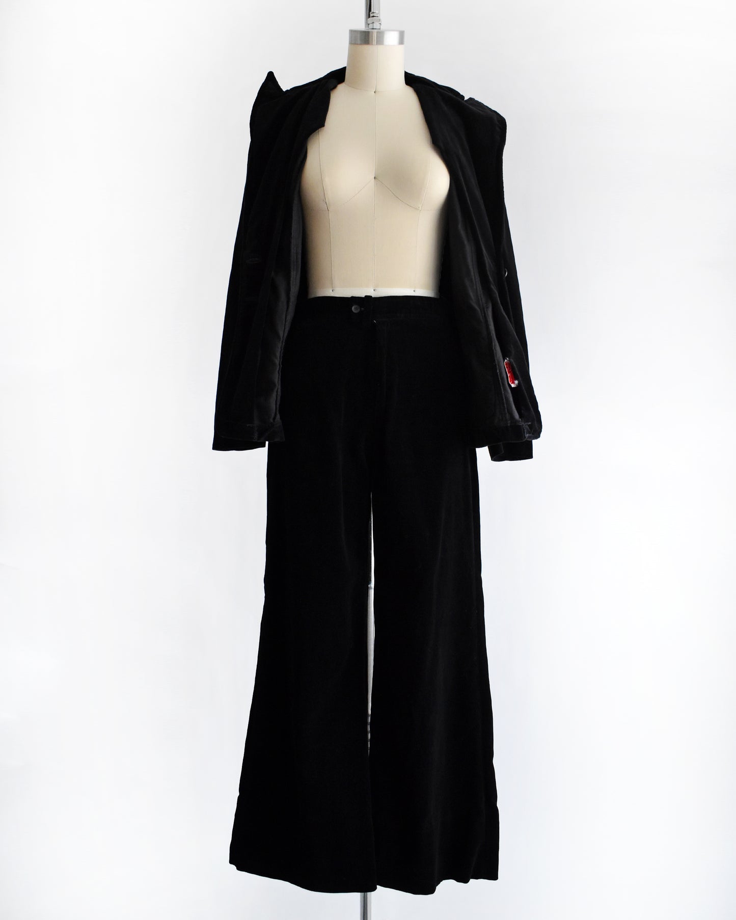 a vintage 1970s black velvet pant set on a mannequin against a white background. the blazer is unbuttoned in this photo