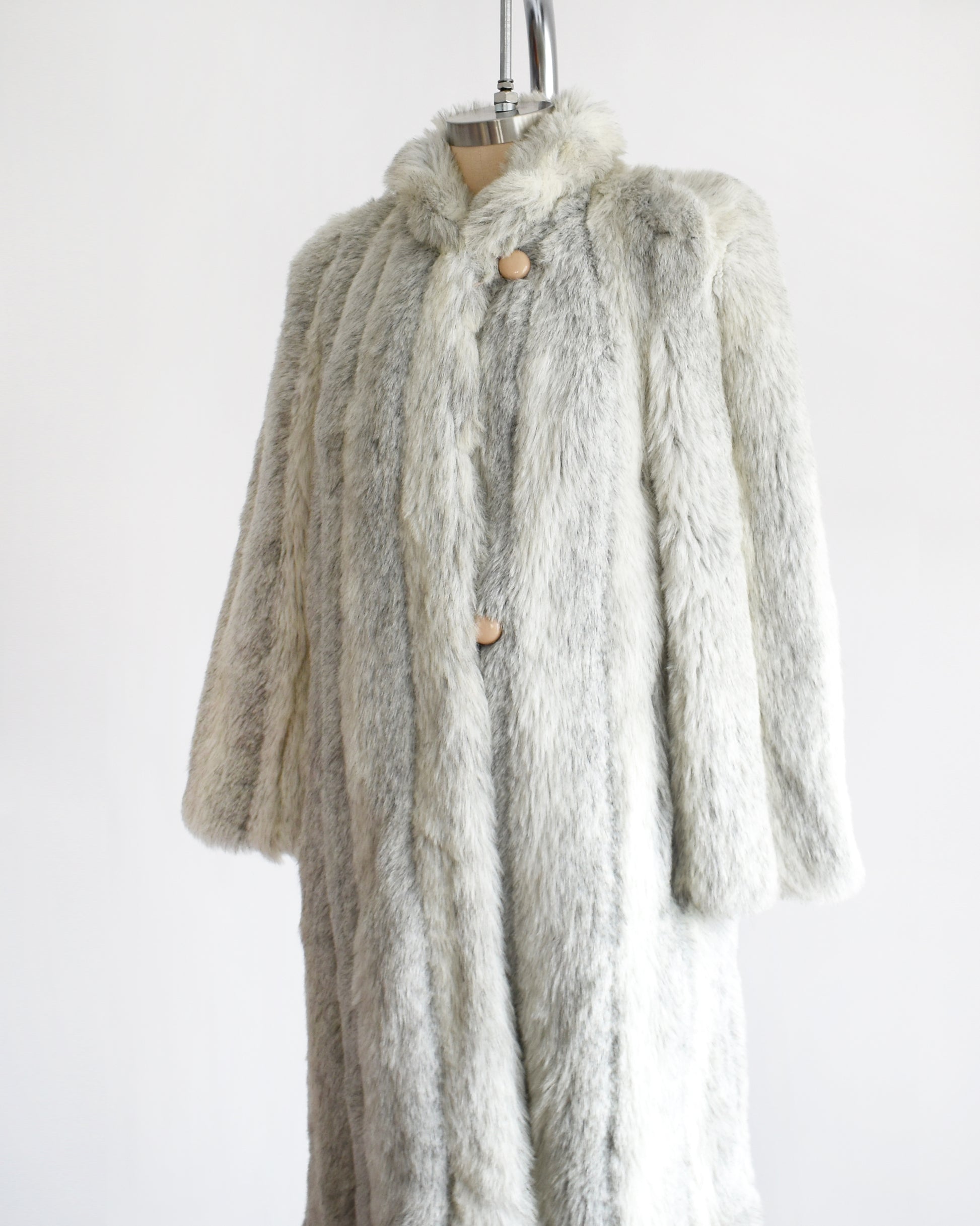 Side front view of a vintage 1980s  cream colored faux fur coat with light and dark gray stripes. 