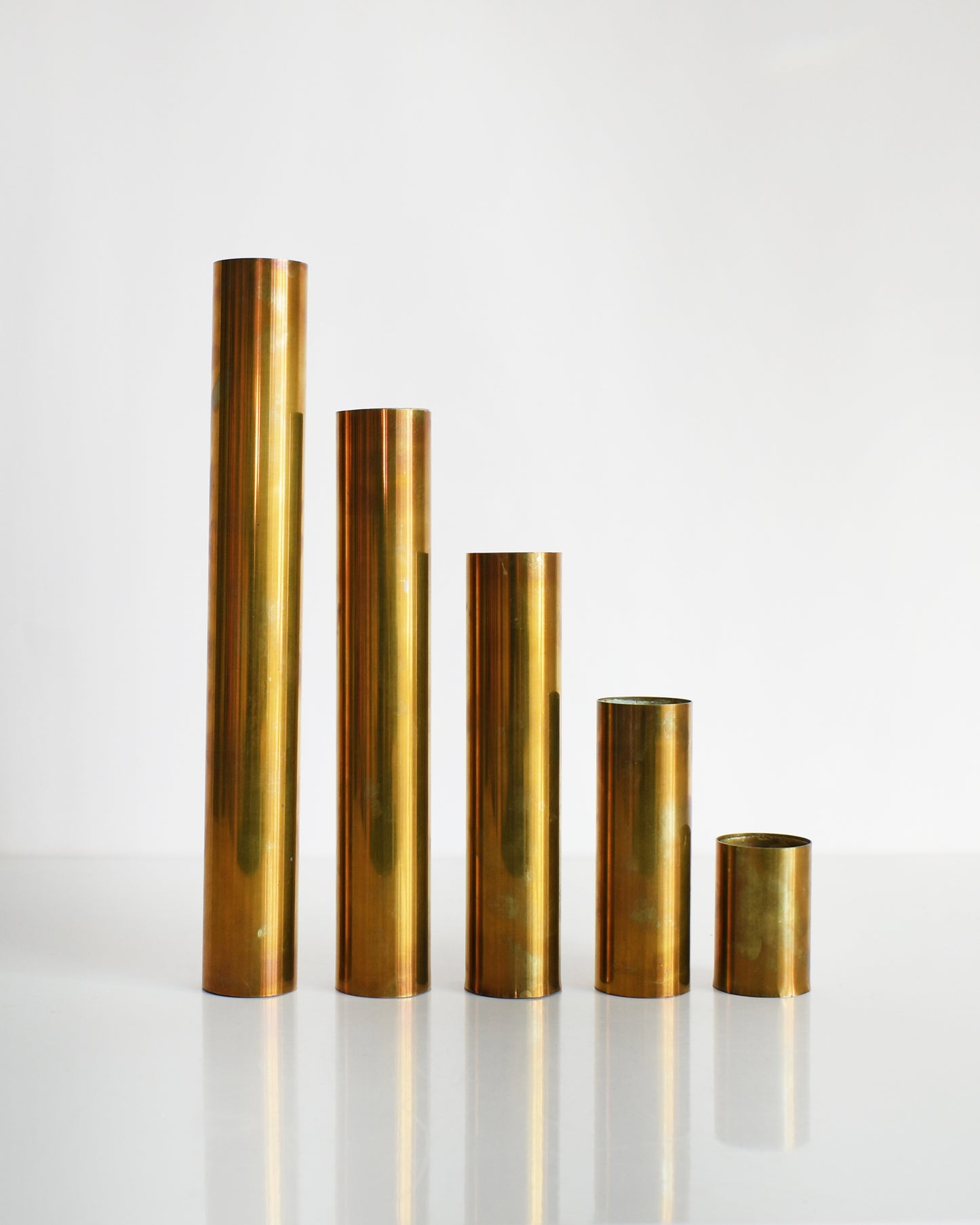 Five mid century brass cylindrical candle holders in different sizes