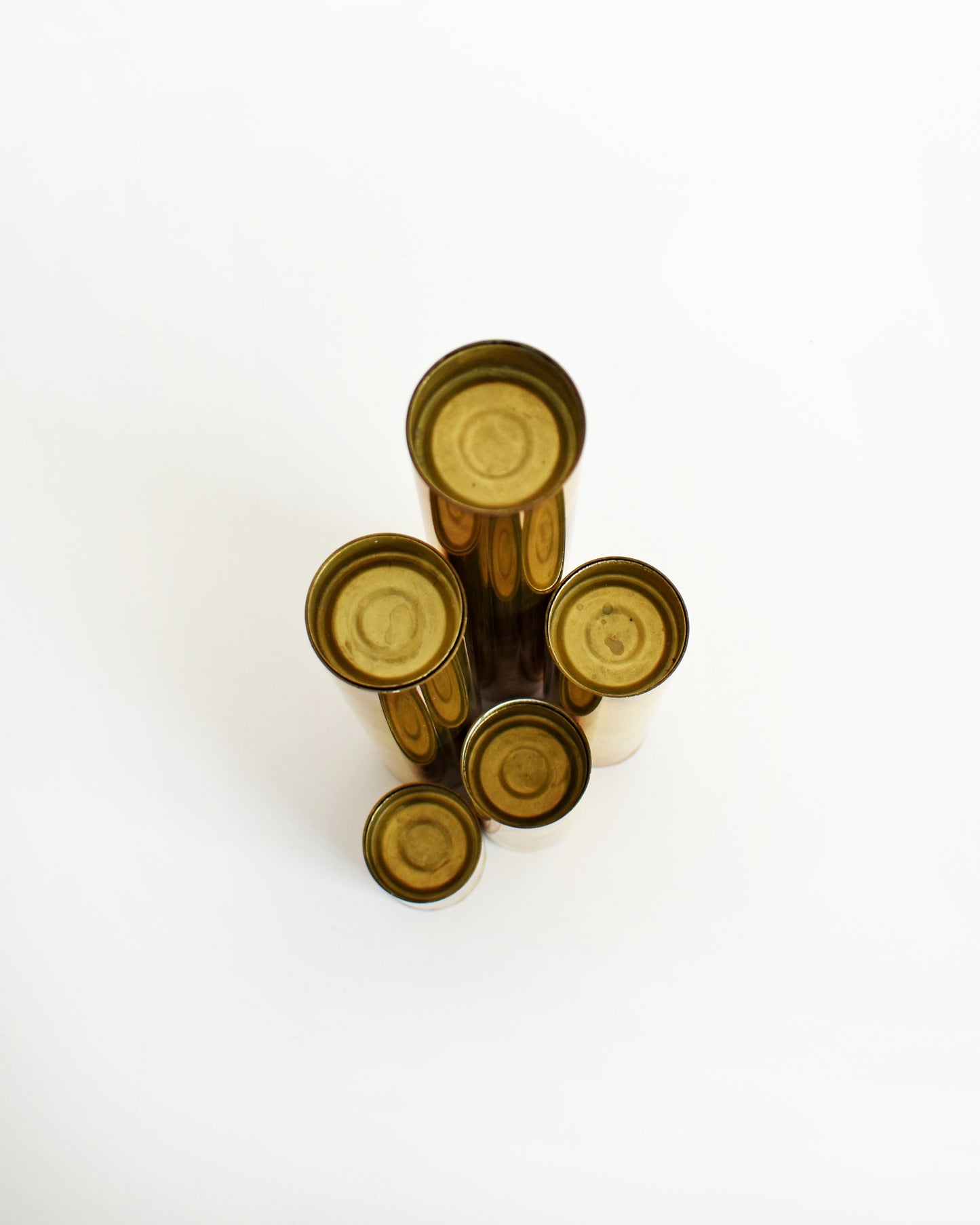 Overhead shot of five brass cylindrical candlesticks