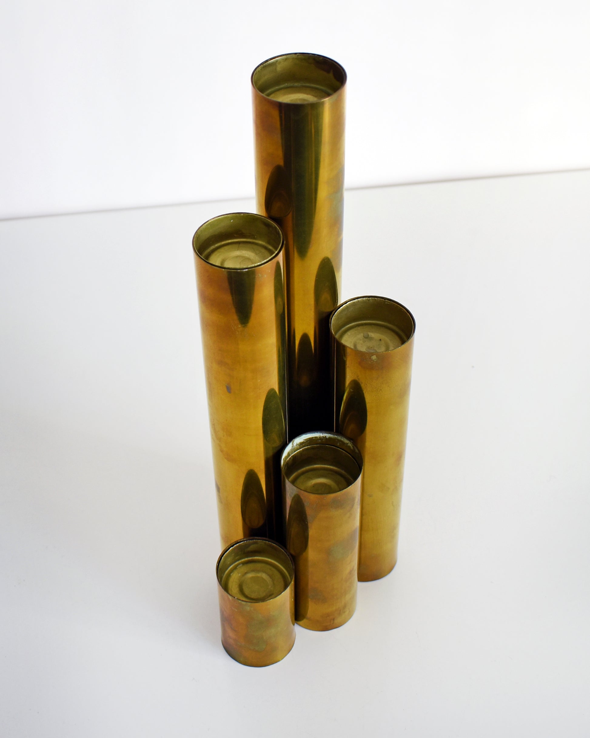 Overhead side shot of five brass cylinder candle holders