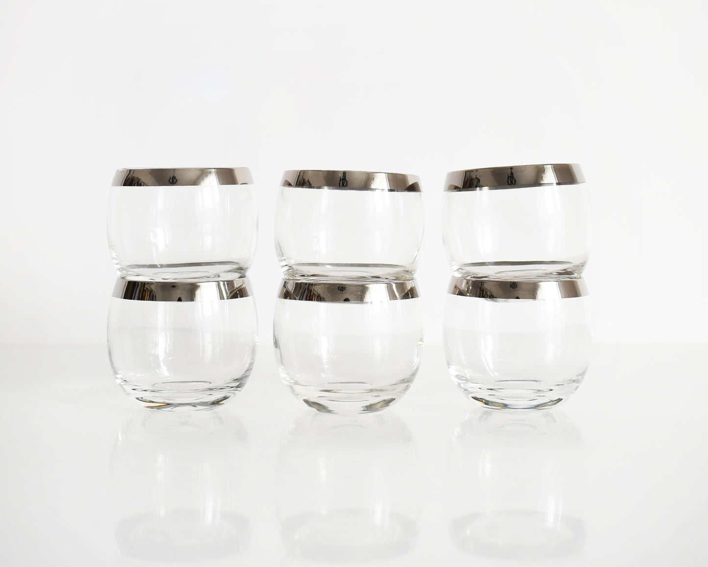 A set of six mid century roly poly glasses with silver rims. The glasses are in a stacked in twos in this photo