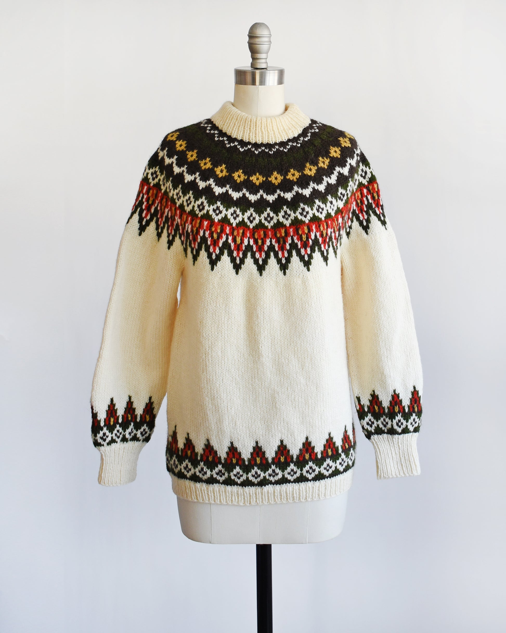 A vintage 1970s cream wool Nordic sweater with a brown, dark green, yellow, and red orange Fair Isle pattern around the collar and complimentary pattern on the hem and cuffs.