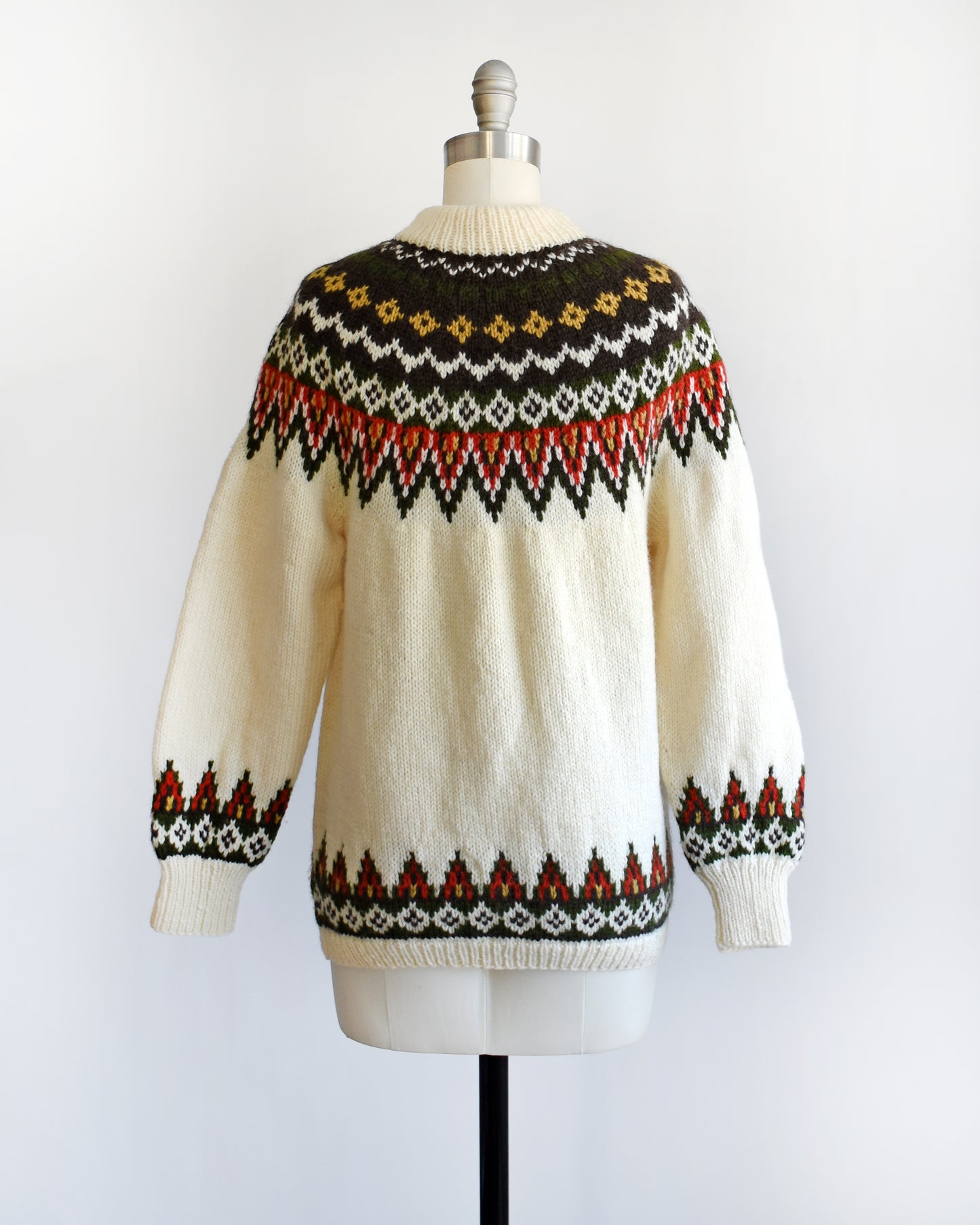 Back view of a vintage 1970s cream wool Nordic sweater with a brown, dark green, yellow, and red orange Fair Isle pattern around the collar and complimentary pattern on the hem and cuffs.