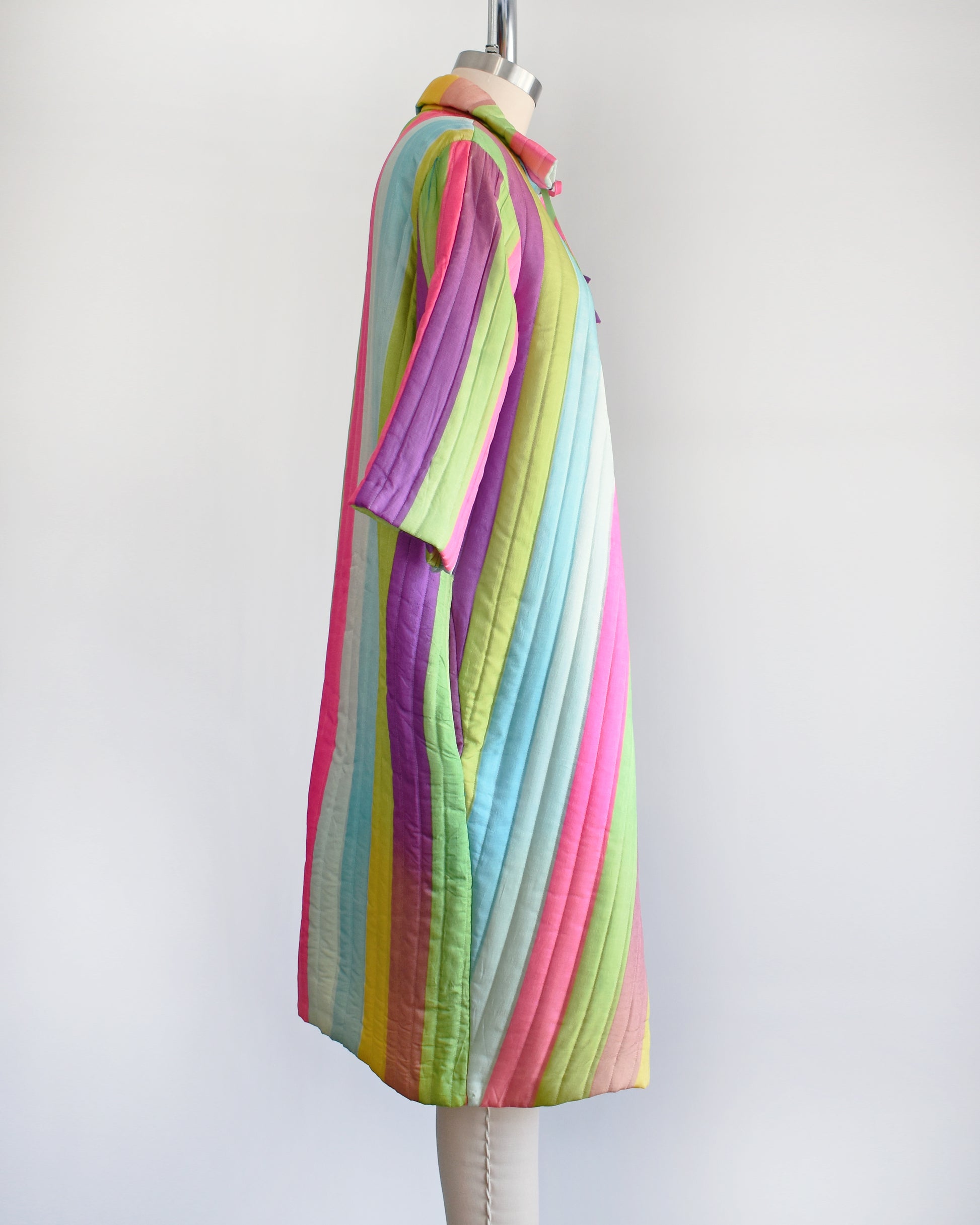 Side view of a vintage 1960s rainbow striped quilted robe with  purple, pink, blue, and green stripes