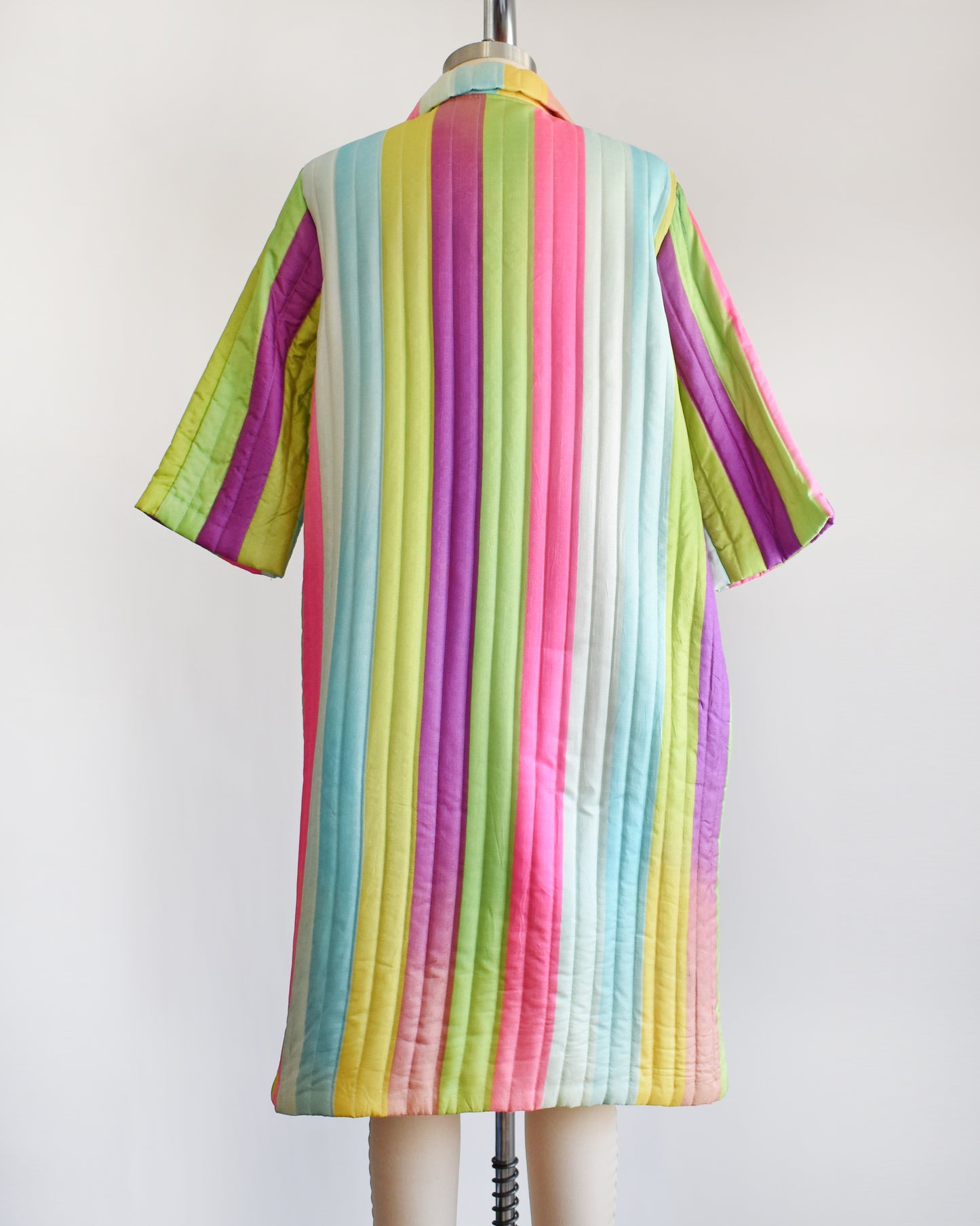 Back view of a vintage 1960s rainbow striped quilted robe with  purple, pink, blue, and green stripes