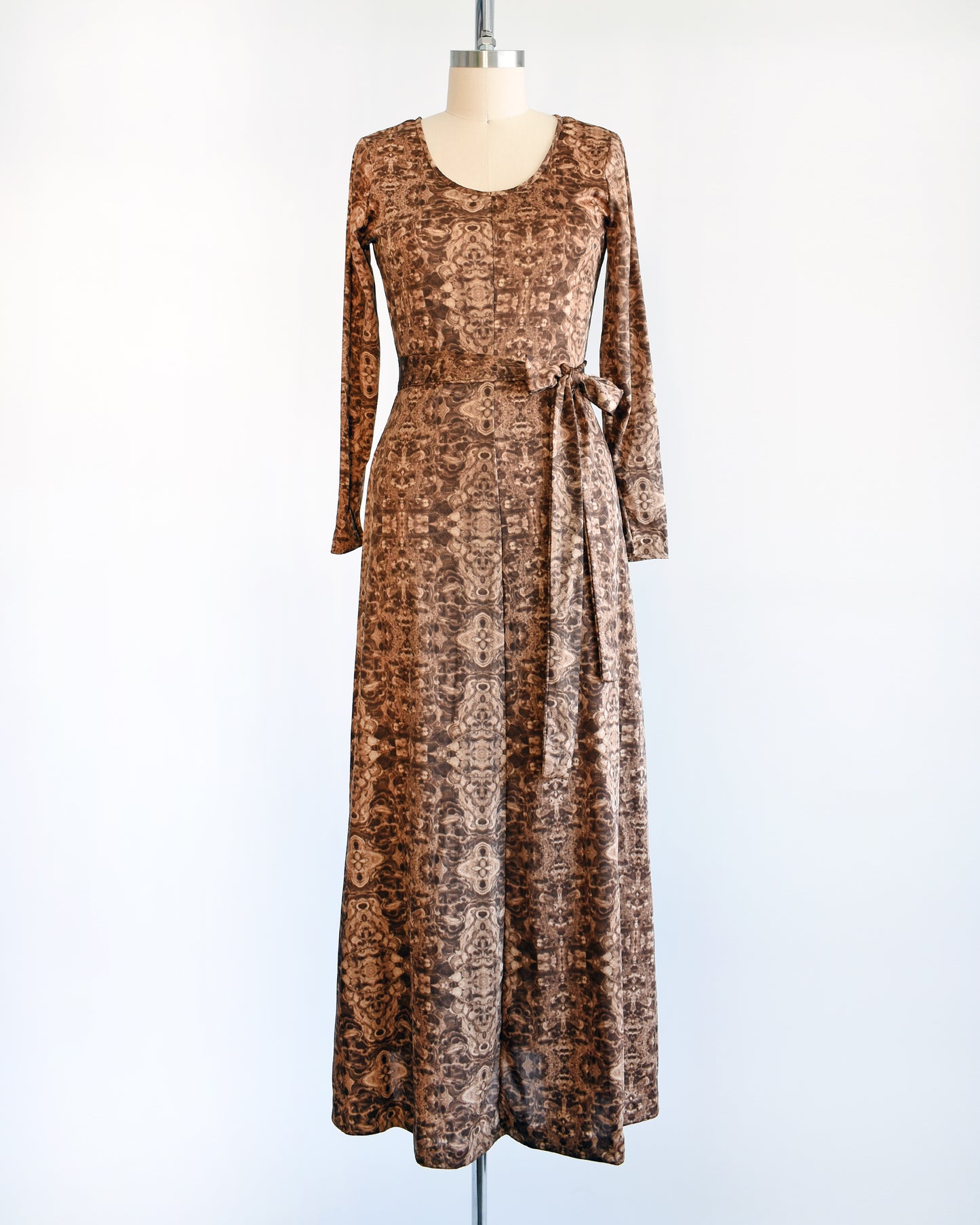 A vintage 1970s long sleeve maxi dress which features a psychedelic kaleidoscope pattern in light and dark brown.