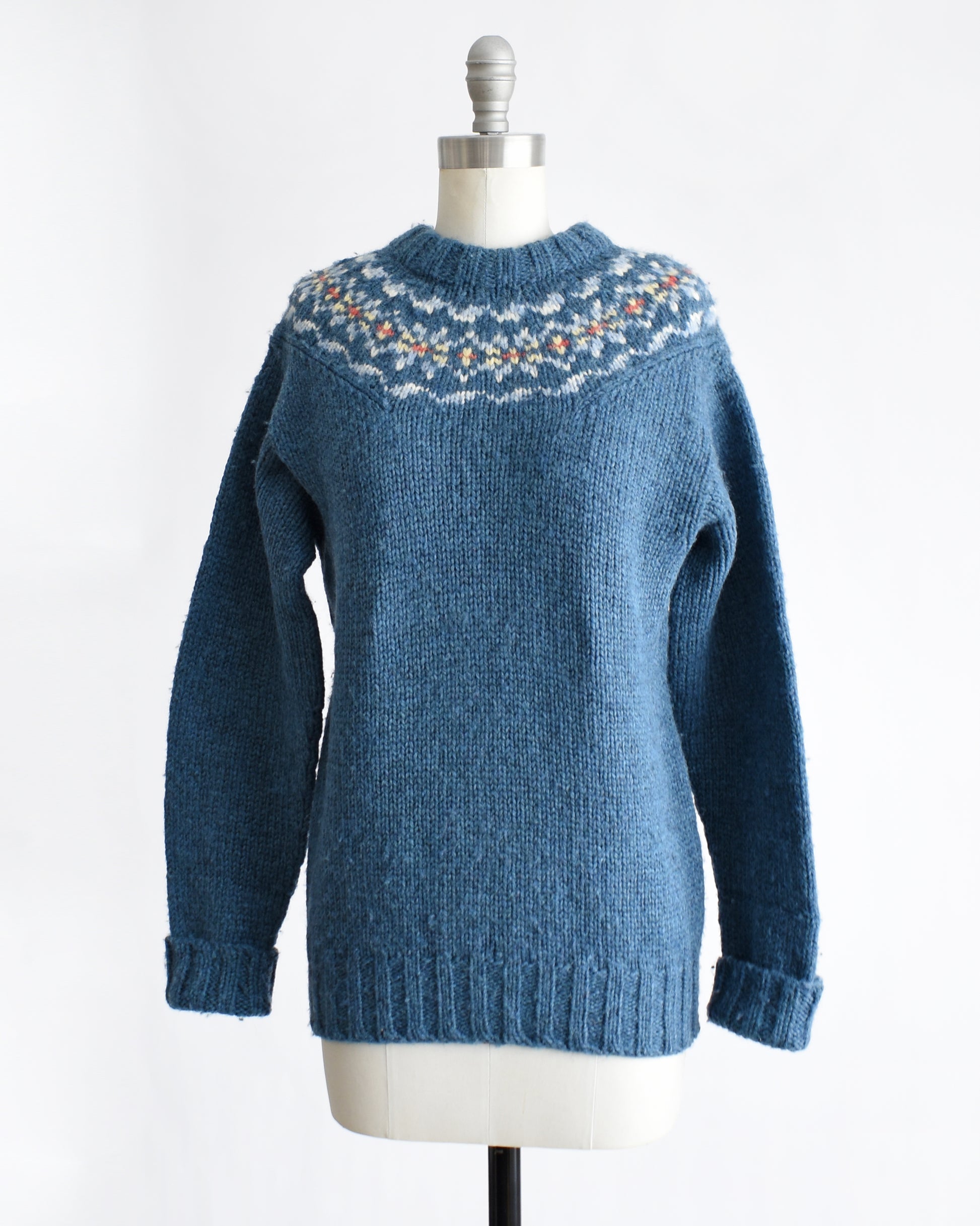side front view of a vintage 1970s blue knitted sweater with patterned yoke on a mannequin against a white background