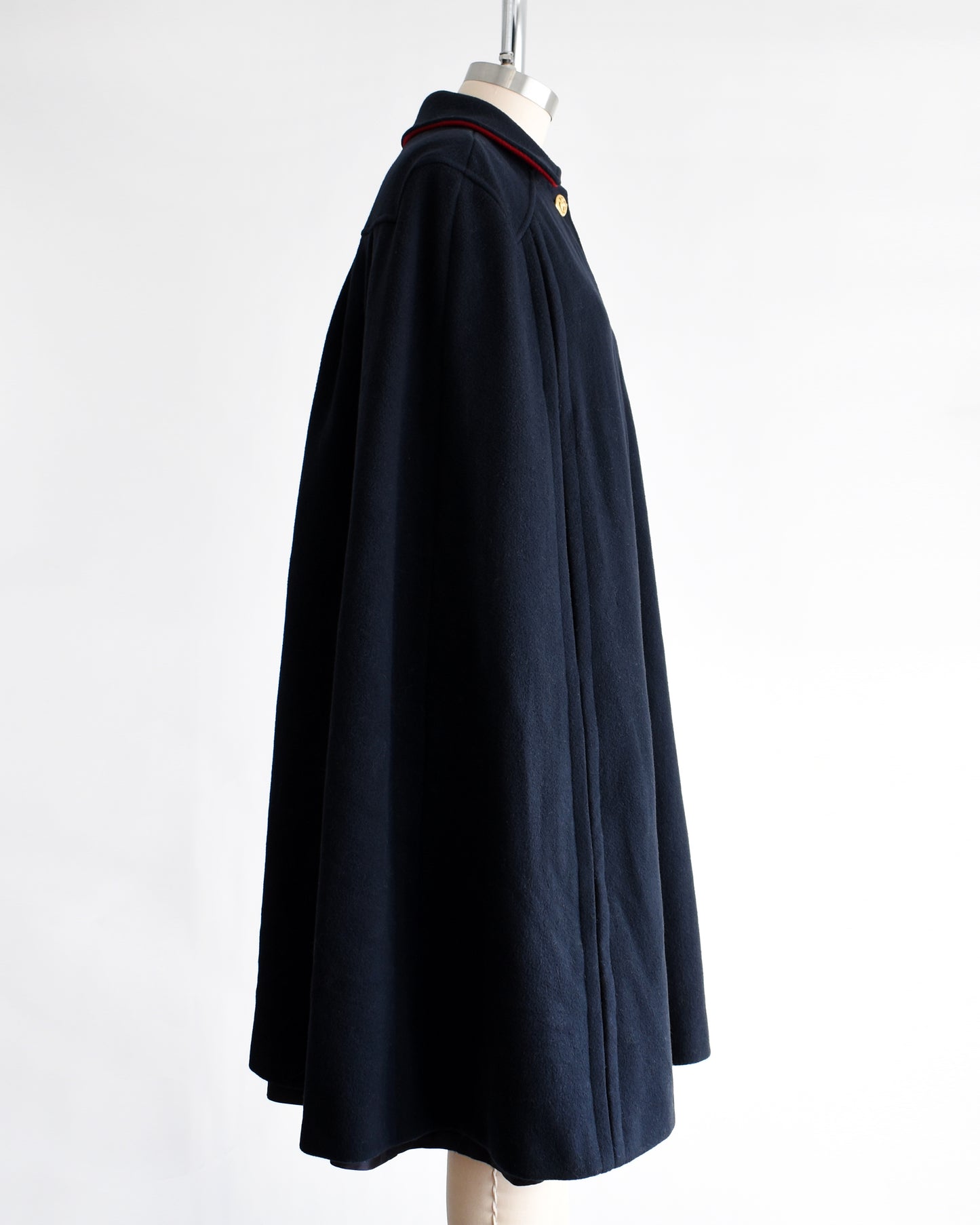 side view of a vintage 1970s navy blue cape on a mannequin against a white background