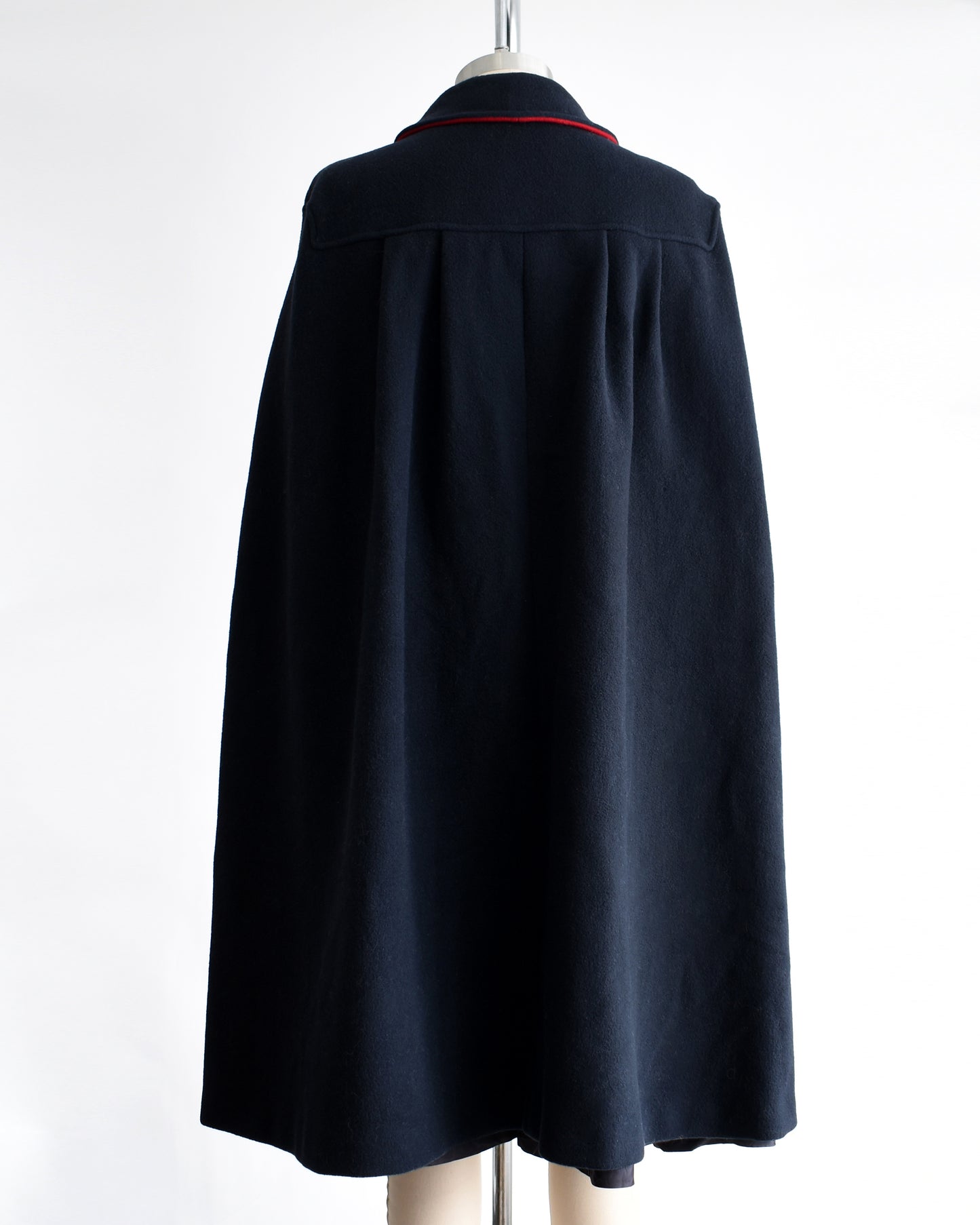 back view of a vintage 1970s navy blue cape on a mannequin against a white background