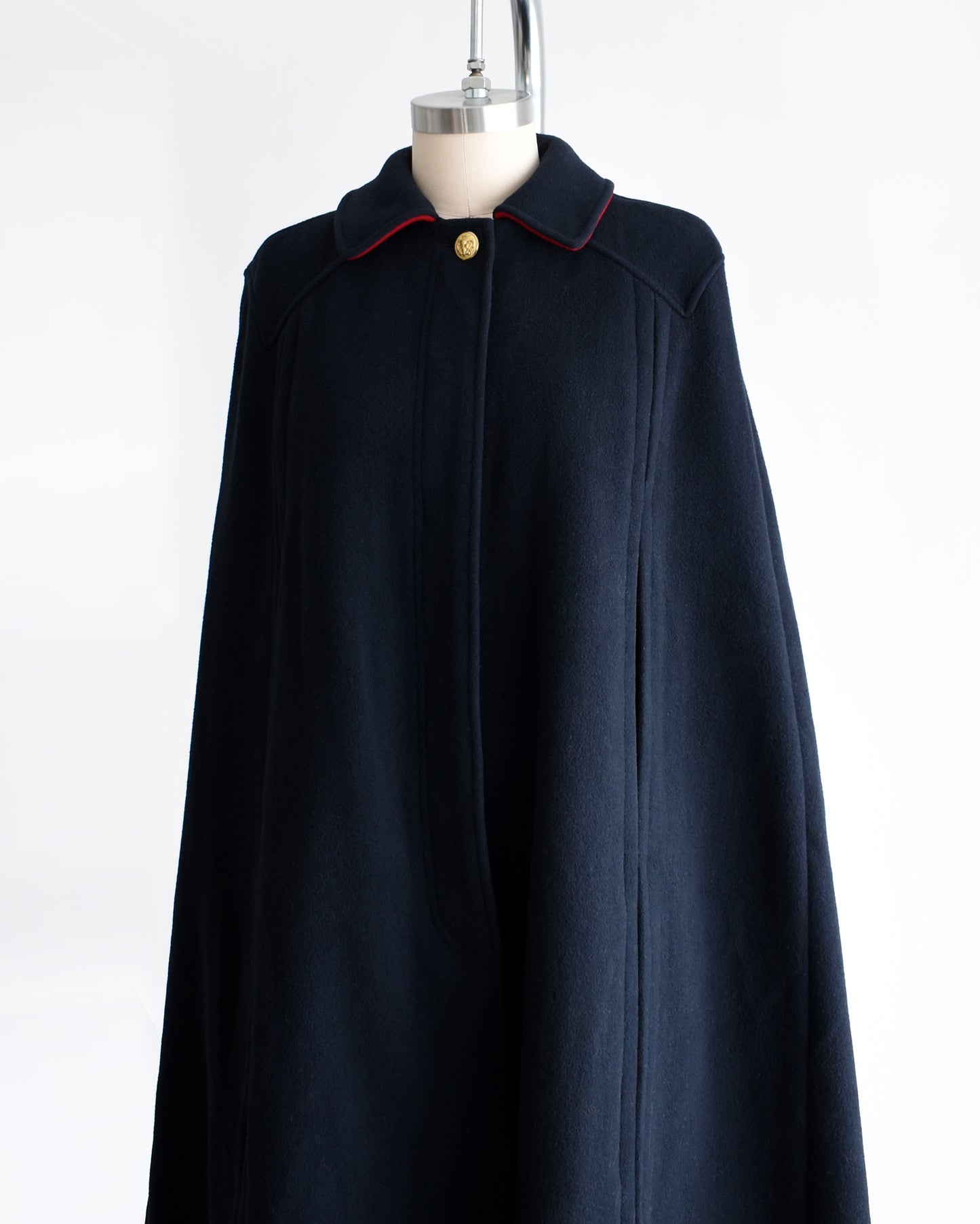 side front view of a vintage 1970s navy blue cape on a mannequin against a white background
