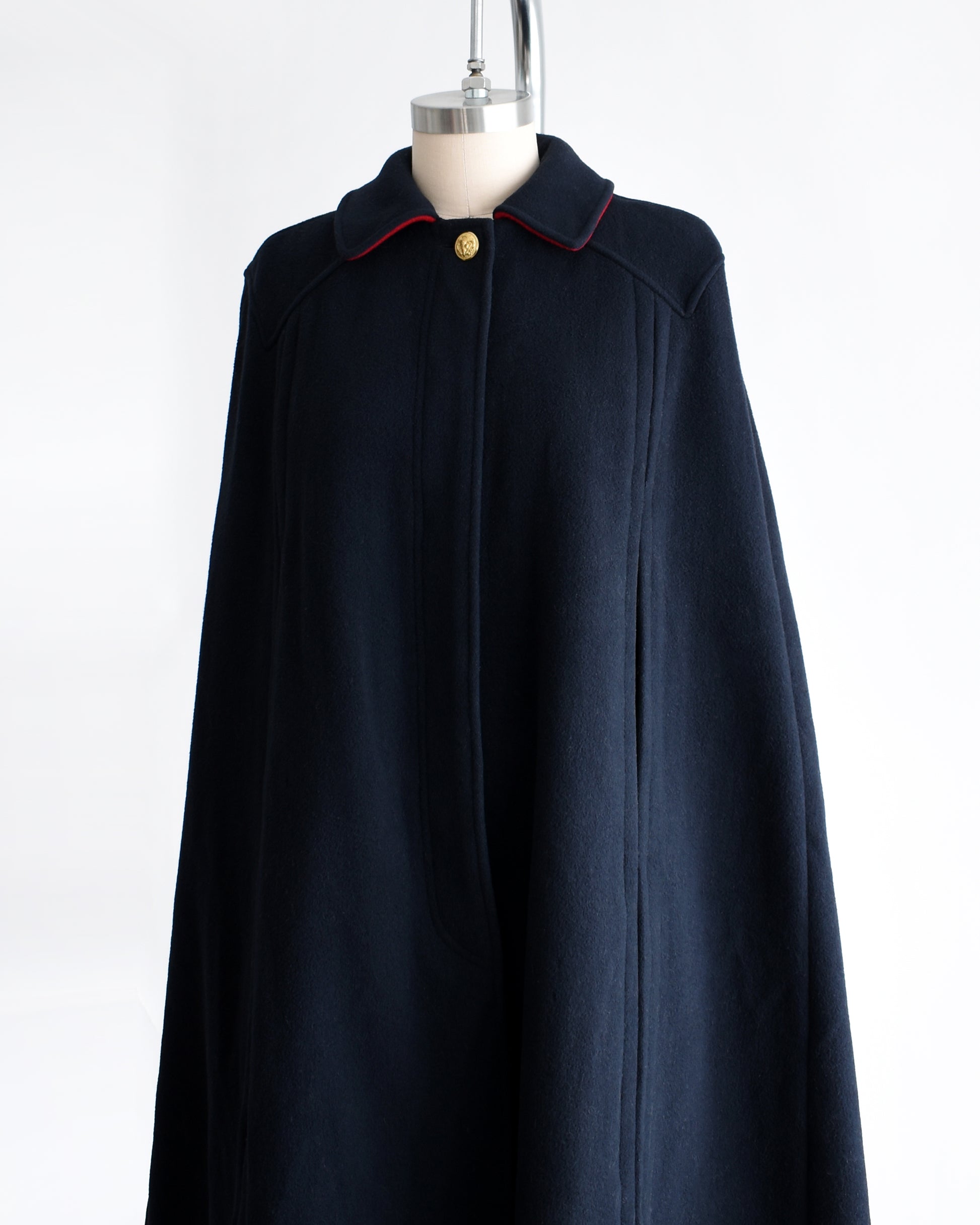 side front view of a vintage 1970s navy blue cape on a mannequin against a white background