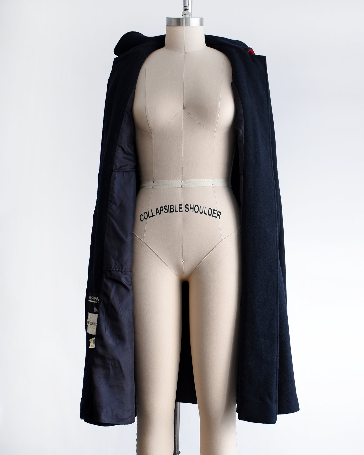 a vintage 1970s navy blue cape on a mannequin against a white background. the cape is unbuttoned in this photo