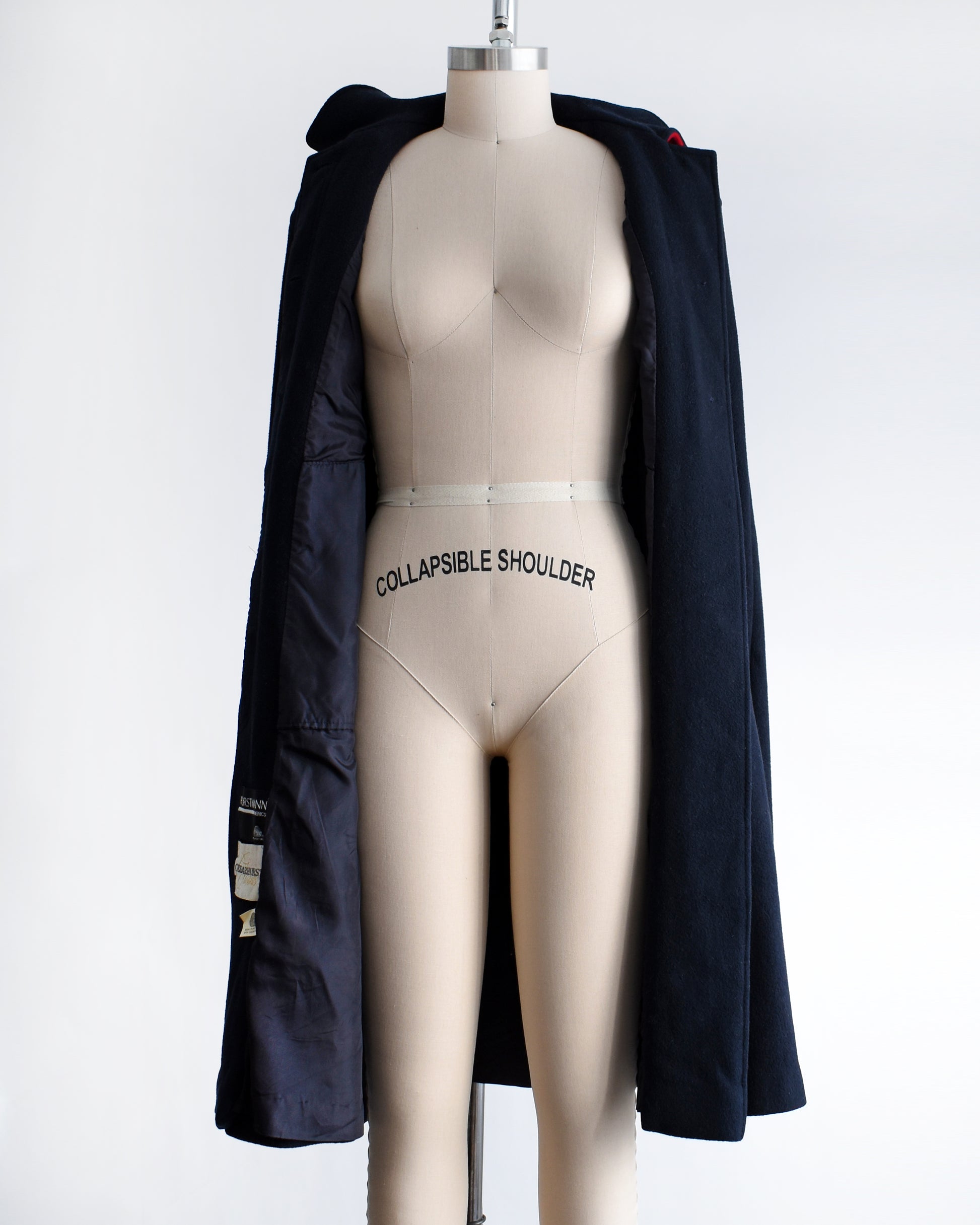 a vintage 1970s navy blue cape on a mannequin against a white background. the cape is unbuttoned in this photo