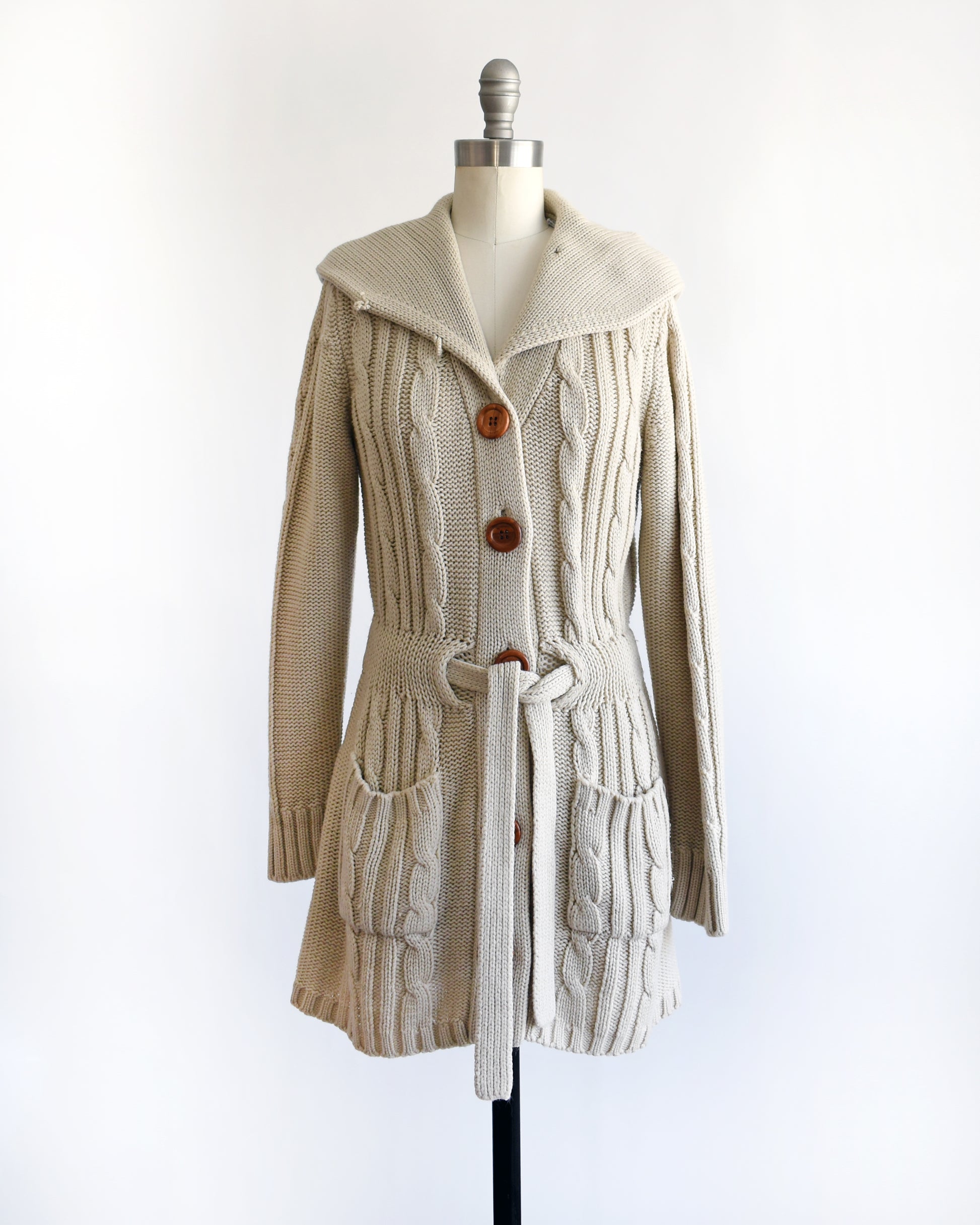 a vintage 1980s beige cable knit cardigan with button details on a mannequin against a white background