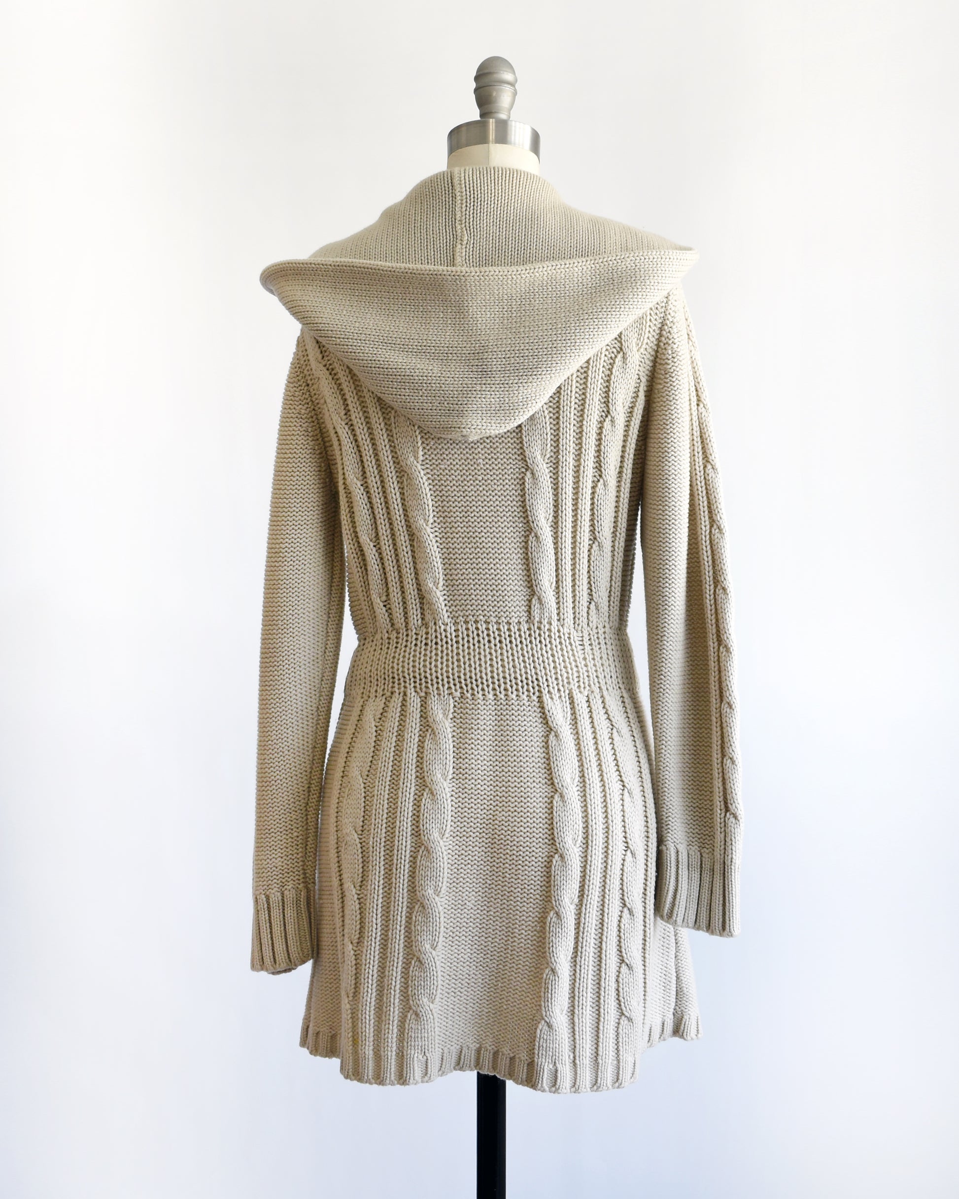 back view of a vintage 1980s beige cable knit cardigan with button details on a mannequin against a white background