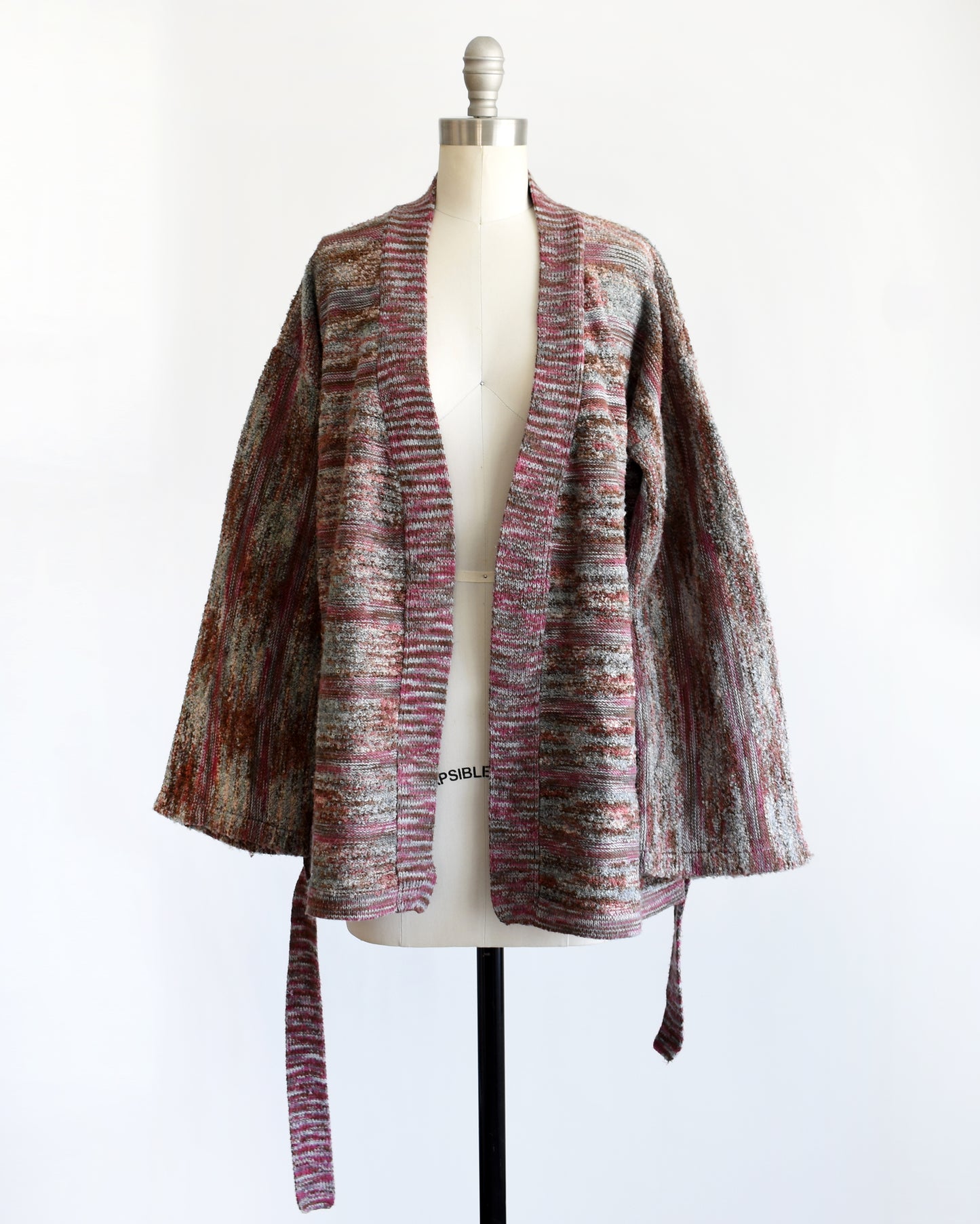 a vintage 1970s space dye wrap cardigan on a dress form against a white background. The cardigan is open in this photo.