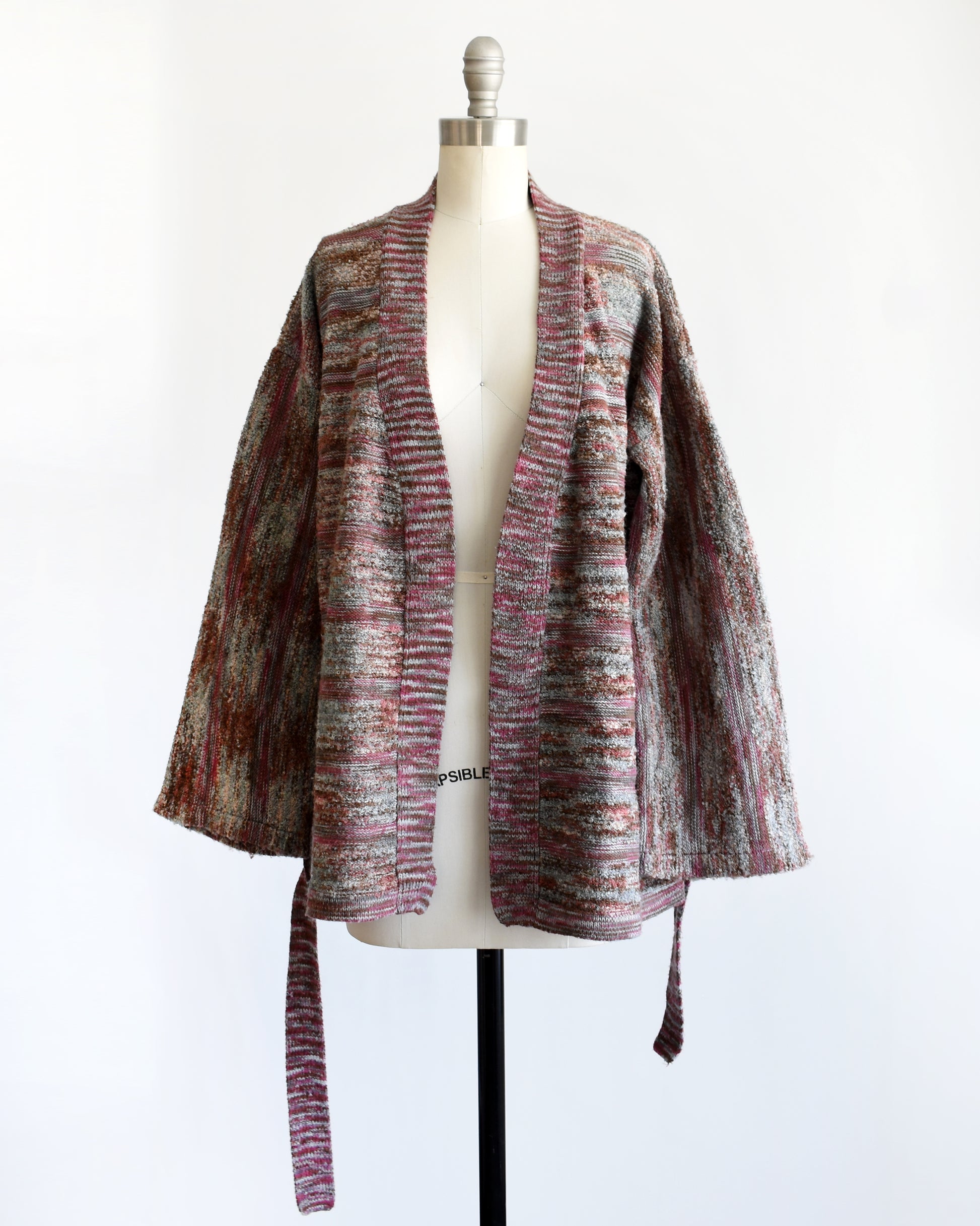 a vintage 1970s space dye wrap cardigan on a dress form against a white background. The cardigan is open in this photo.