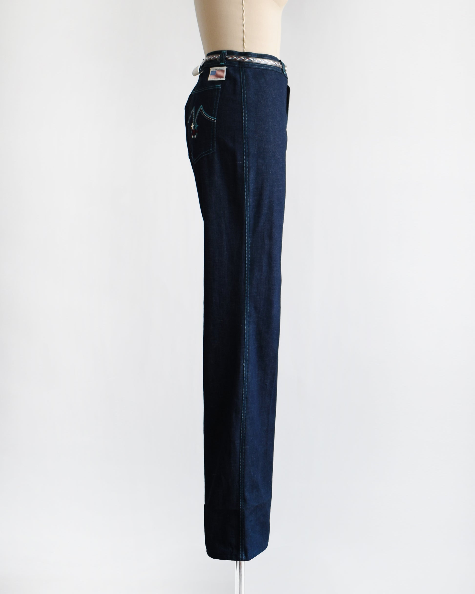 side view of a pair of vintage 1970s dark blue wide leg jeans on a mannequin on a white background