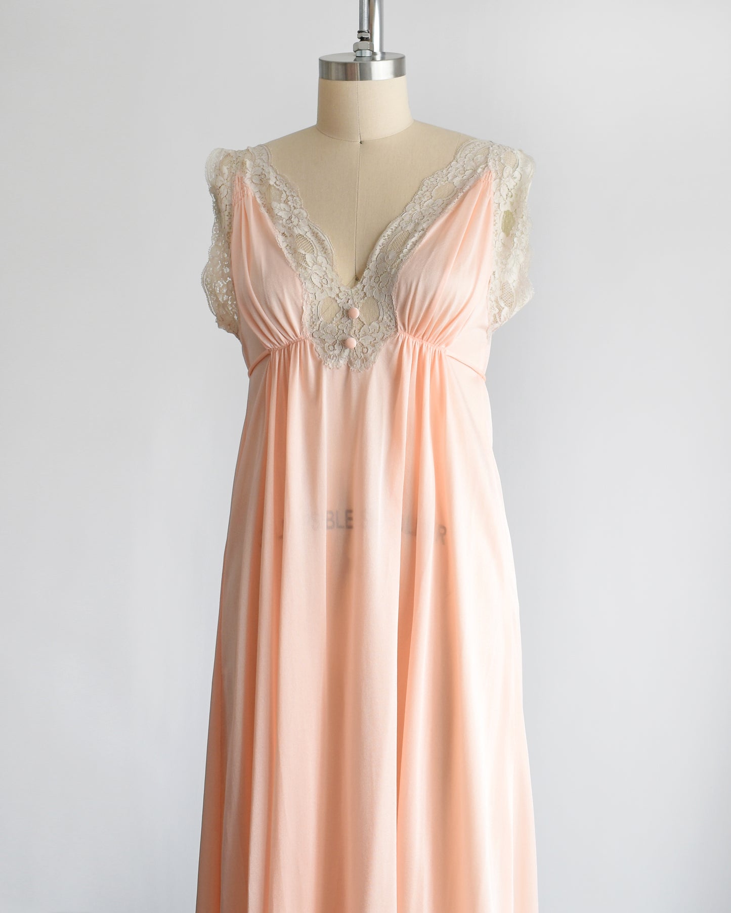 Side front view of a vintage 1970s peach nightgown with lace trim