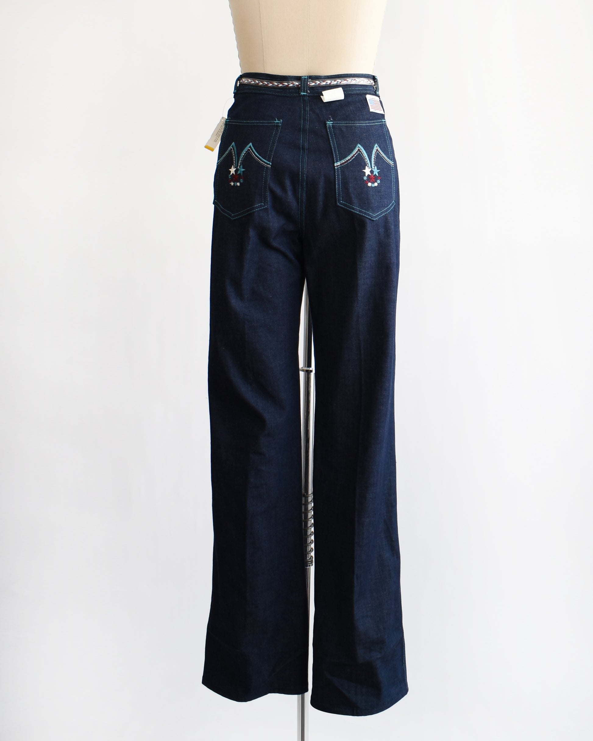 back view of a pair of vintage 1970s dark blue wide leg jeans on a mannequin on a white background