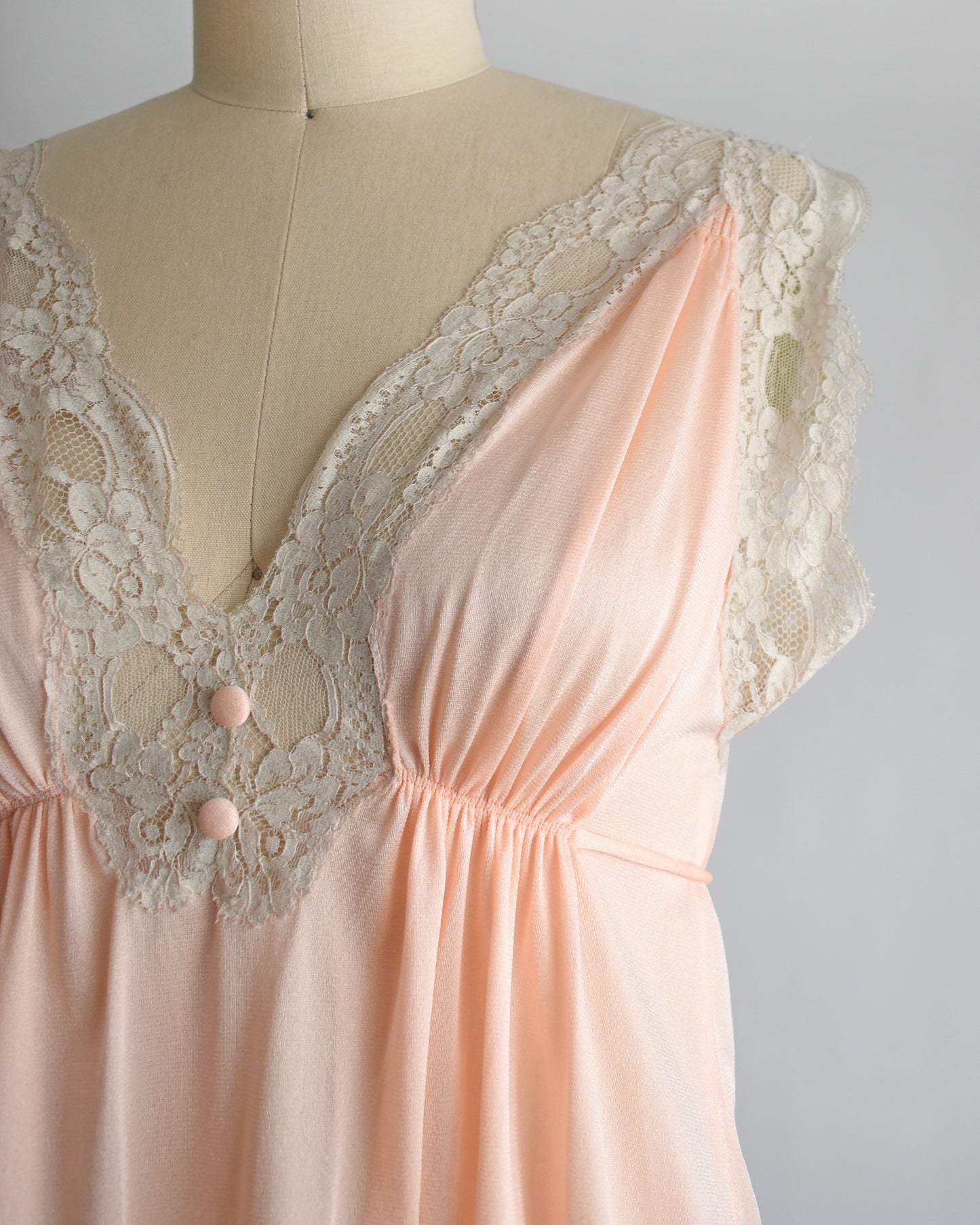 Close up of the lace trim on the bodice of a vintage 1970s peach nightgown