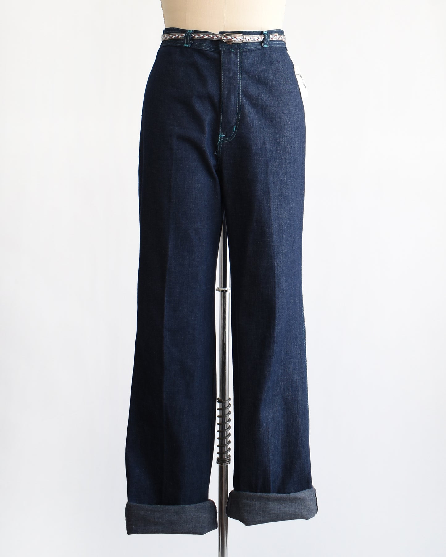 a pair of vintage 1970s dark blue wide leg jeans on a mannequin on a white background. The cuffs are rolled in this photo.