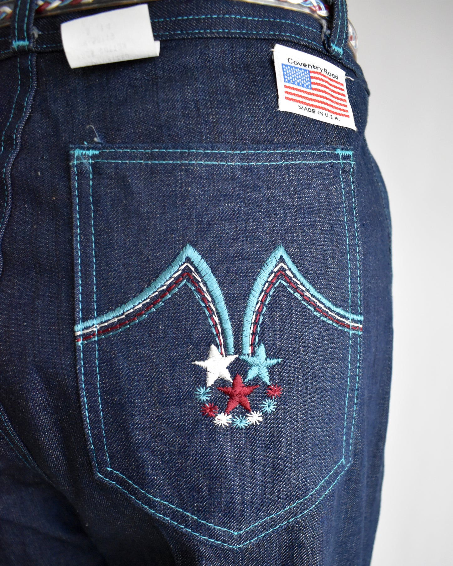 Close-up of blue denim jeans with decorative stitching and a flag label.