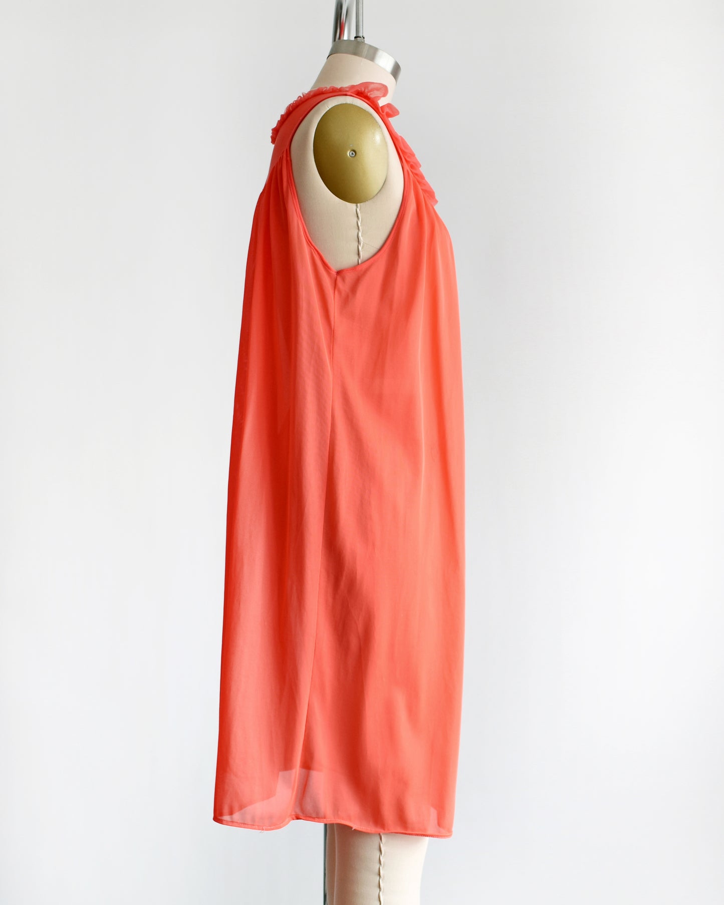 side view of a vintage 1960s/1970s hot coral ruffle nightie that has a ruffled neckline
