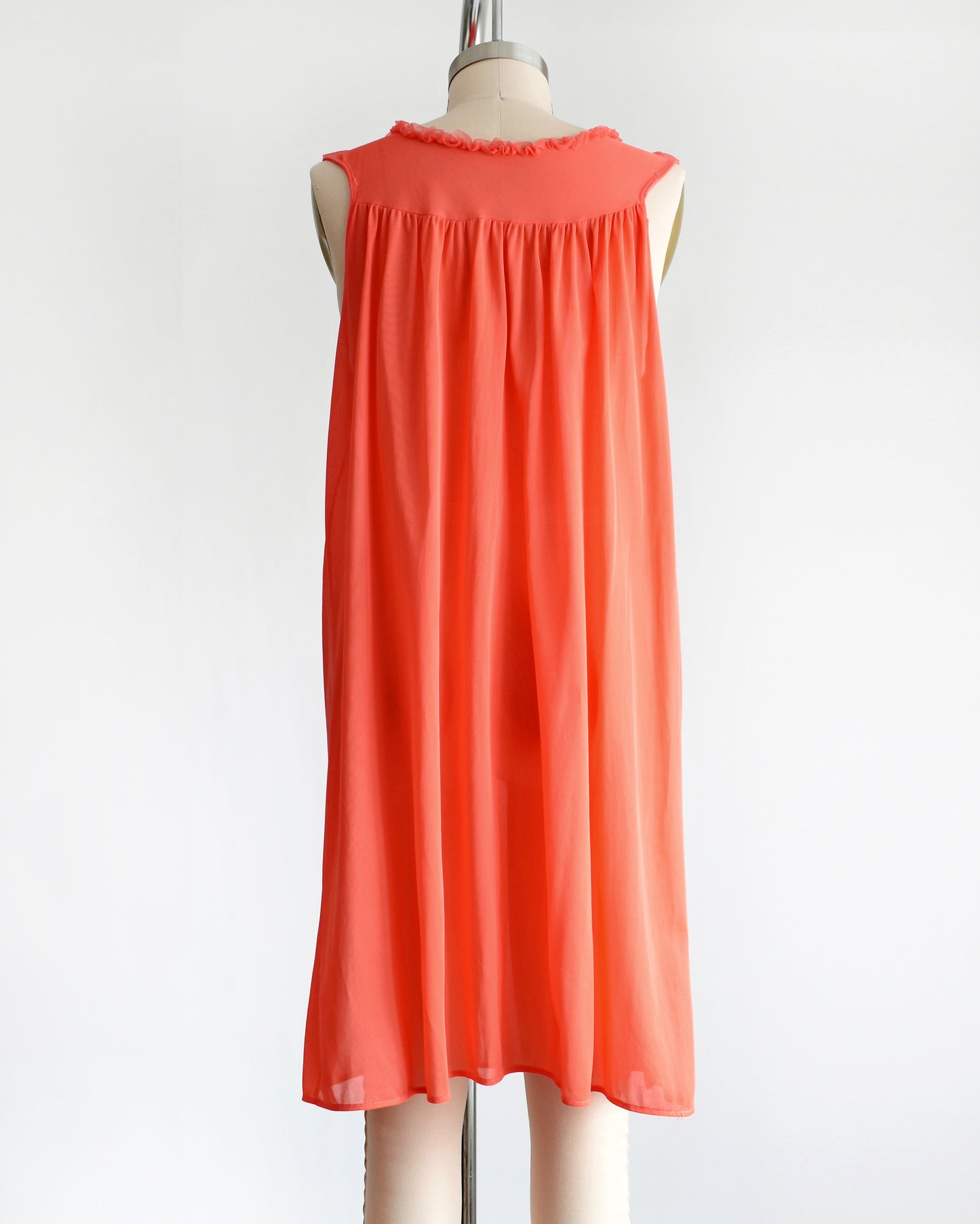back view of a vintage 1960s/1970s hot coral ruffle nightie that has a ruffled neckline