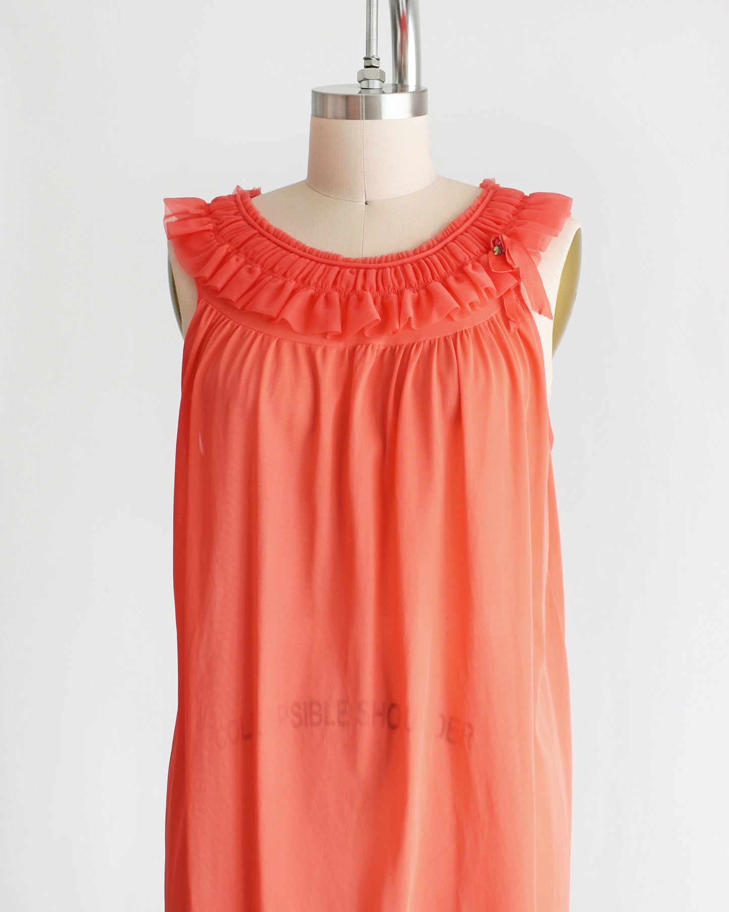 side front view of a vintage 1960s/1970s hot coral ruffle nightie that has a ruffled neckline