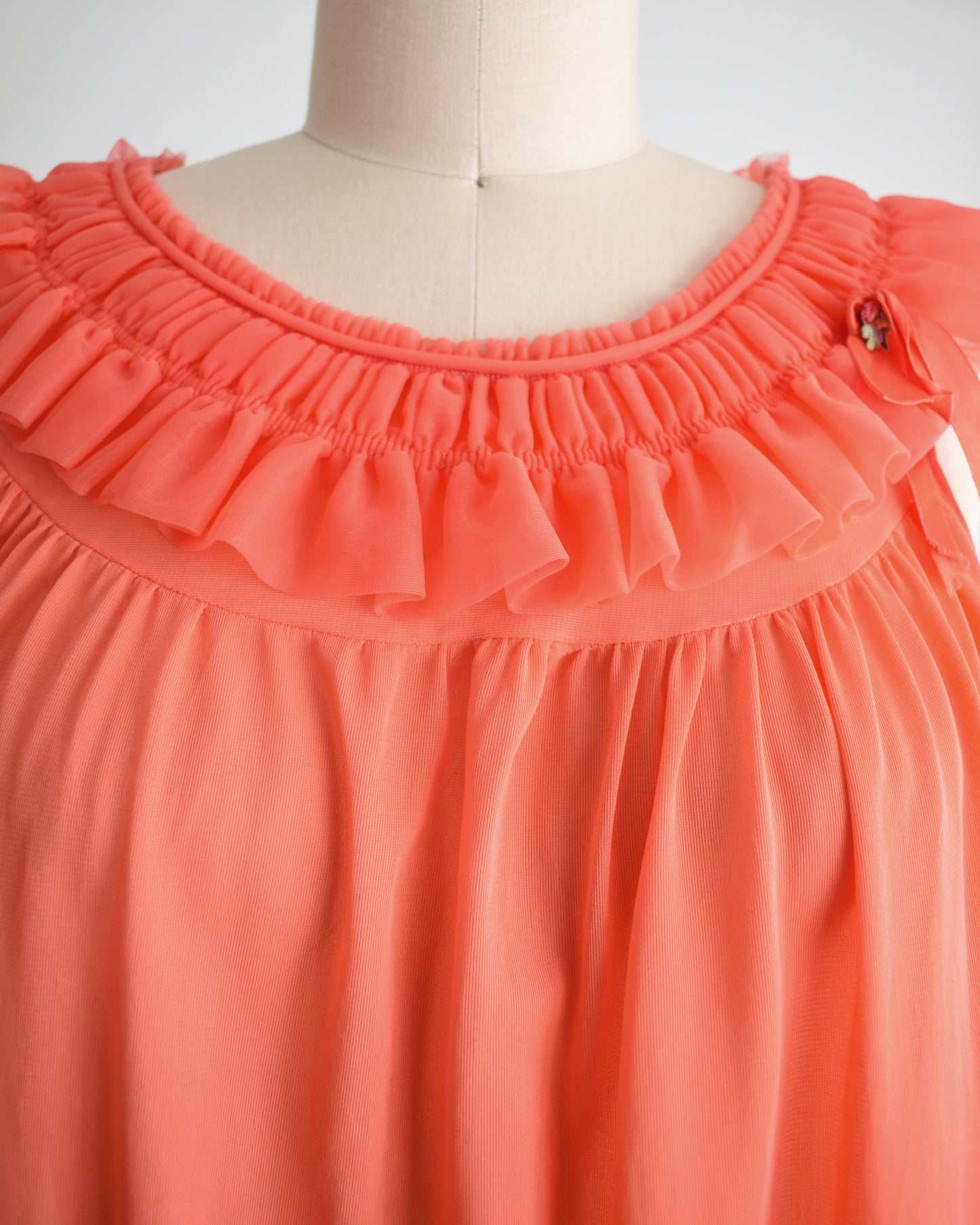close up of the ruffled neckline and small embroidered flower