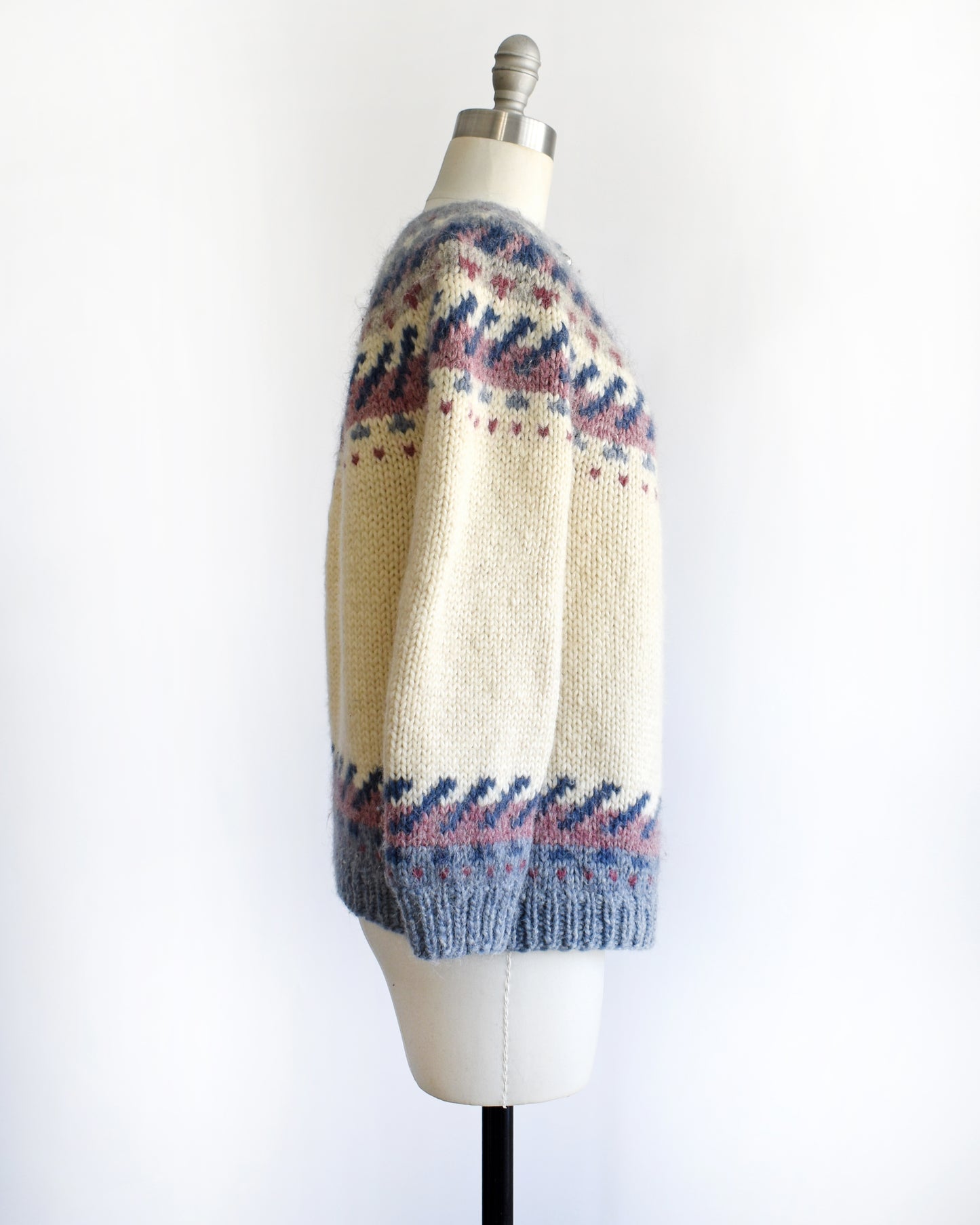 side view of a vintage 1970s Icelandic knitted sweater with a pattern on a mannequin against a white background