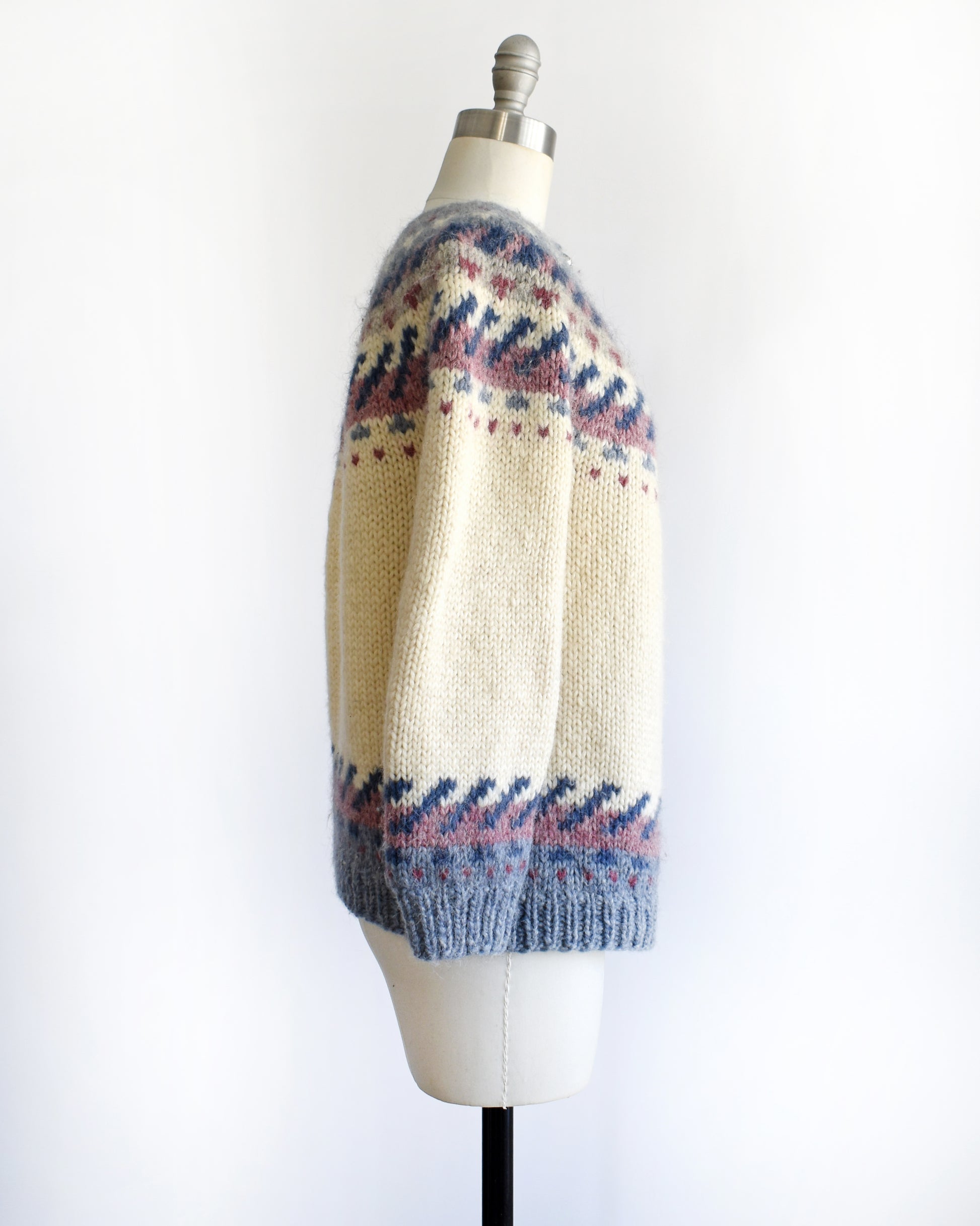 side view of a vintage 1970s Icelandic knitted sweater with a pattern on a mannequin against a white background
