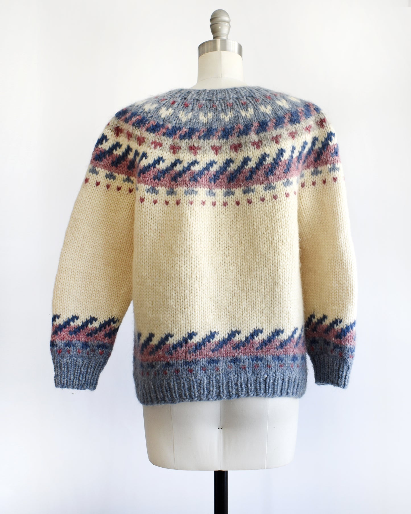 back view of a vintage 1970s Icelandic knitted sweater with a pattern on a mannequin against a white background