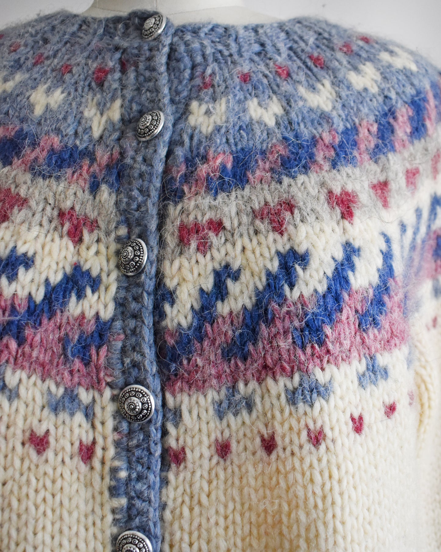 Close-up of a knitted cardigan with a patterned design and button details.