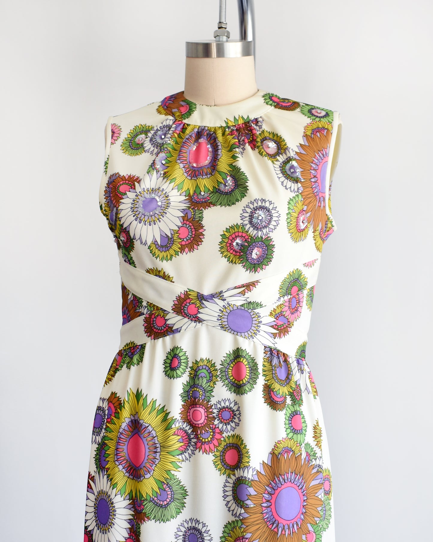 side front view of a vintage 1970s colorful floral dress on a mannequin against a white background