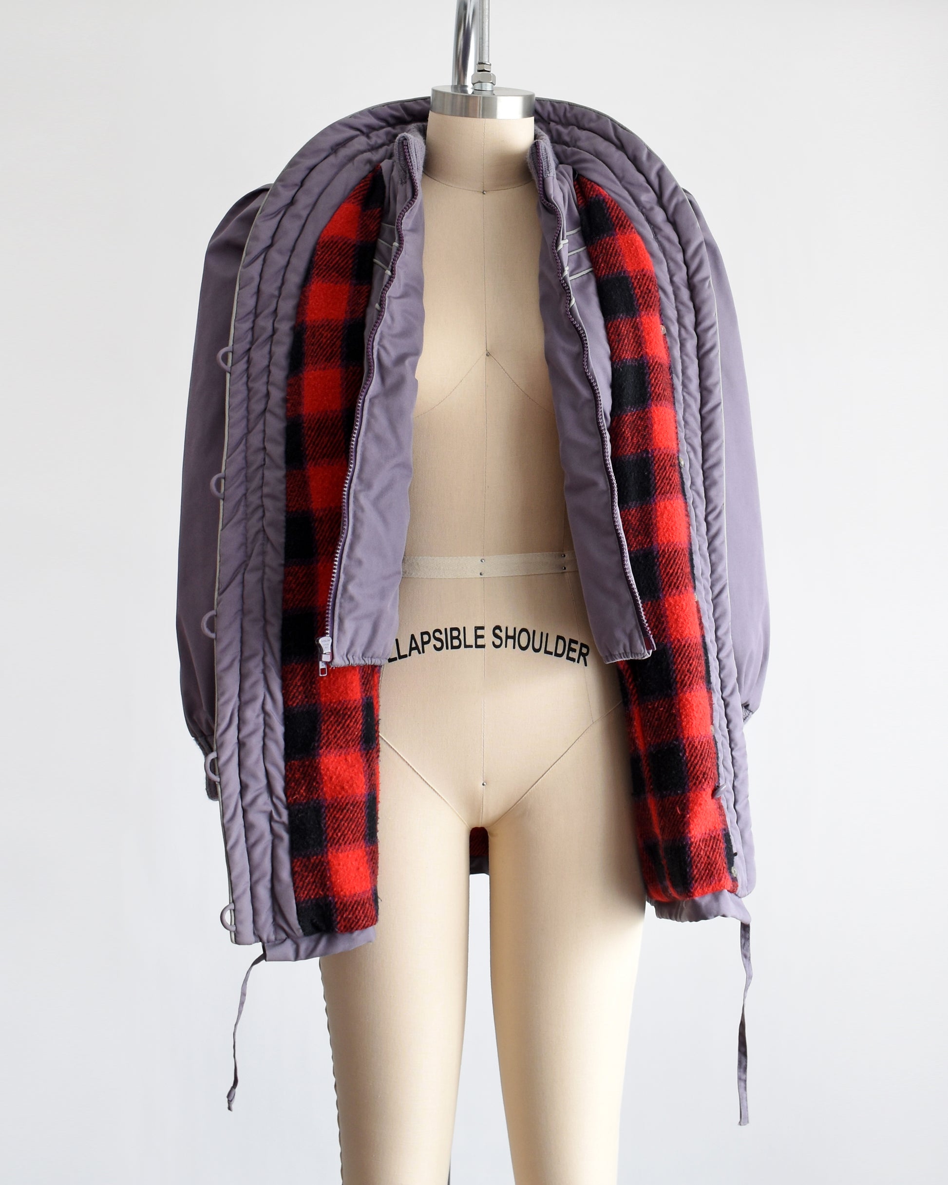  a vintage 1980s purple puffy coat with shawl style collar with gray trim. The coat is unbuttoned and unzipped showing the plaid lining