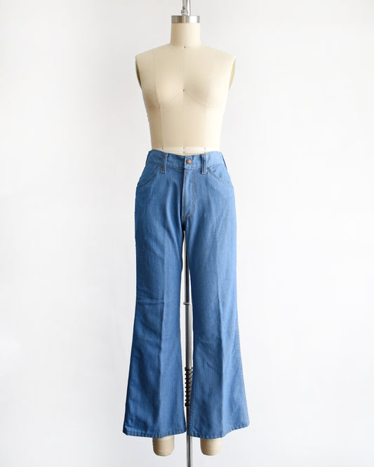 a vintage 1970s pair of bell bottom blue jeans on a mannequin against a white background