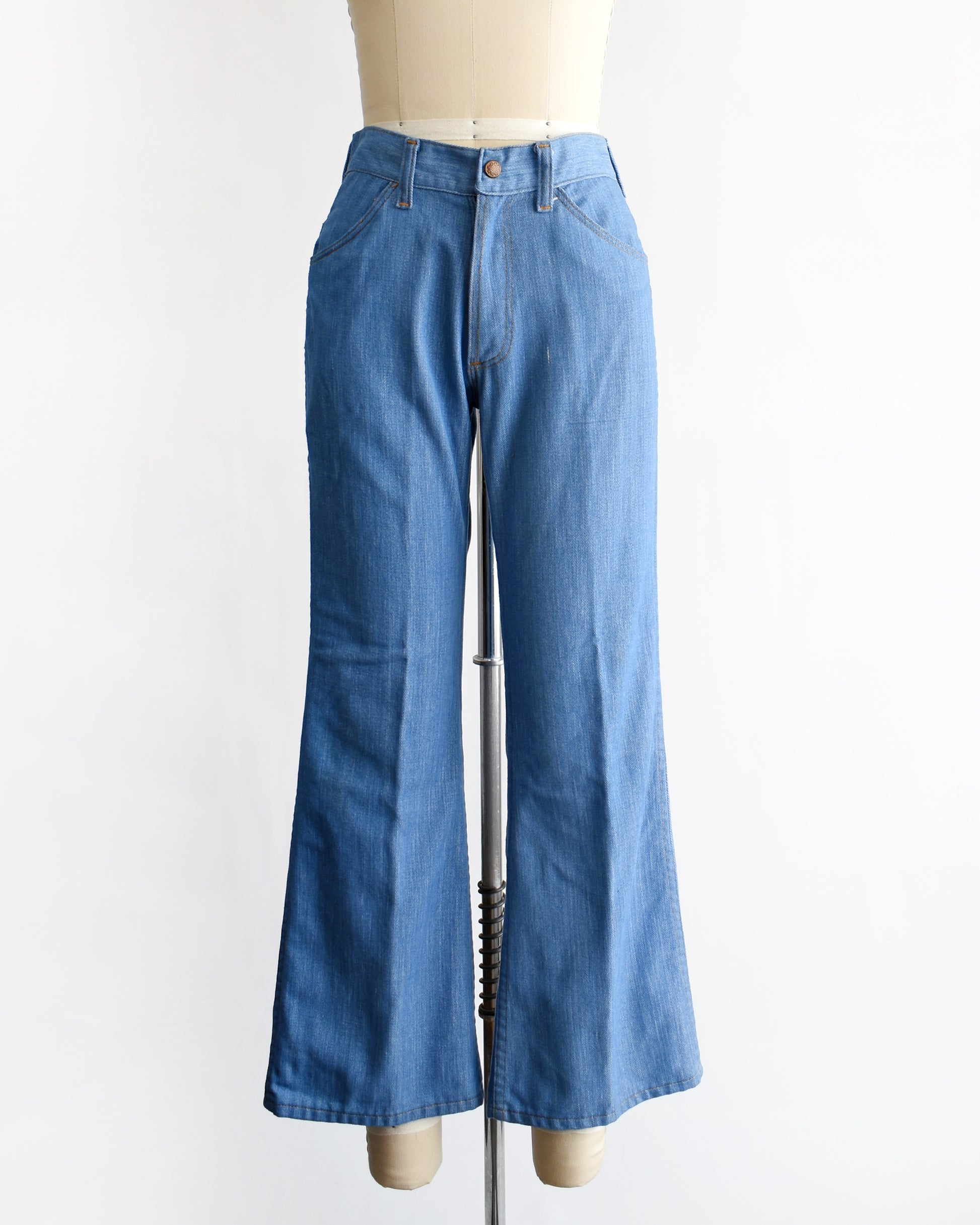 a vintage 1970s pair of bell bottom blue jeans on a mannequin against a white background