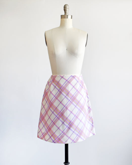 a vintage 1960s pink and purple plaid skirt on a mannequin against a white background