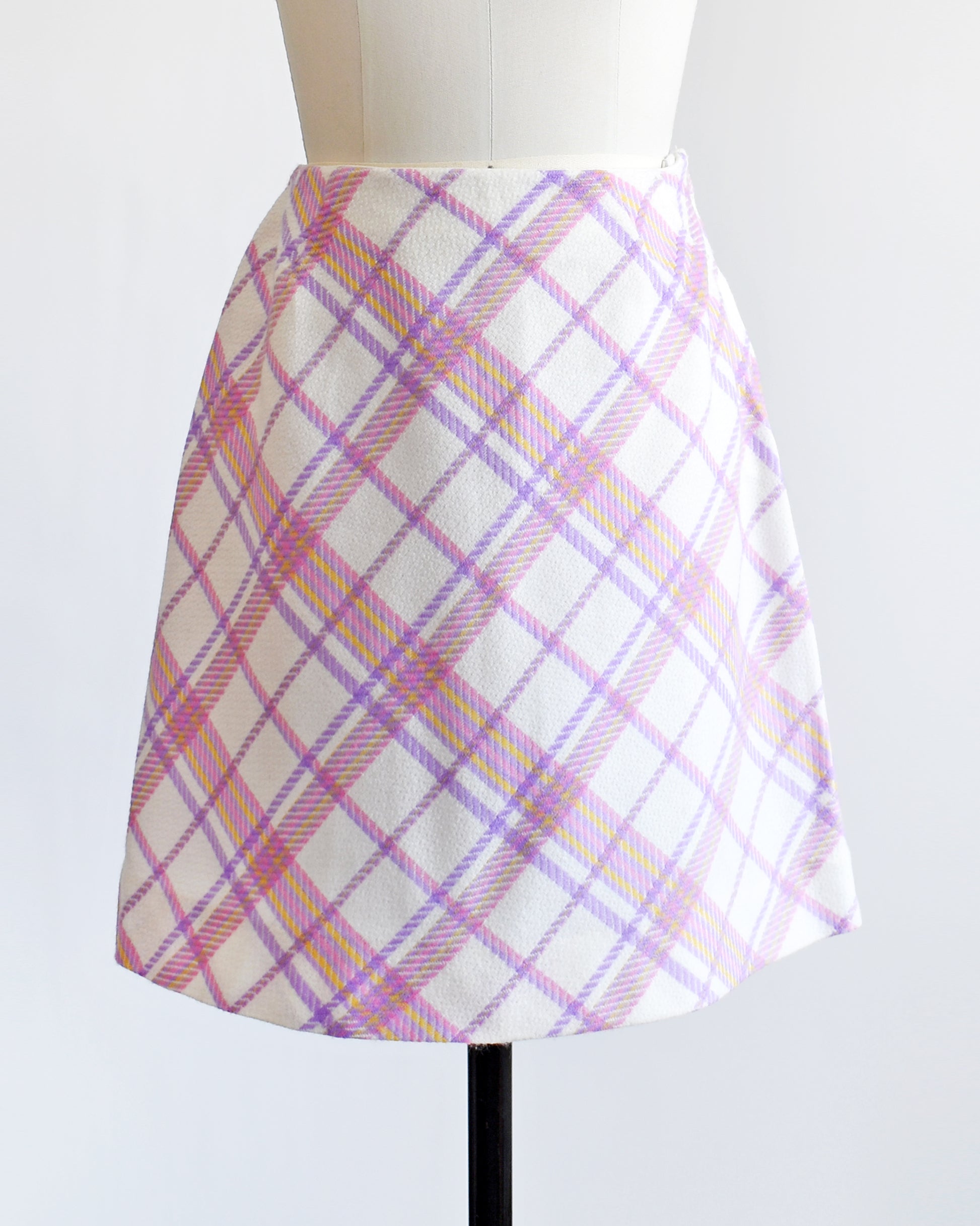 a vintage 1960s pink and purple plaid skirt on a mannequin against a white background