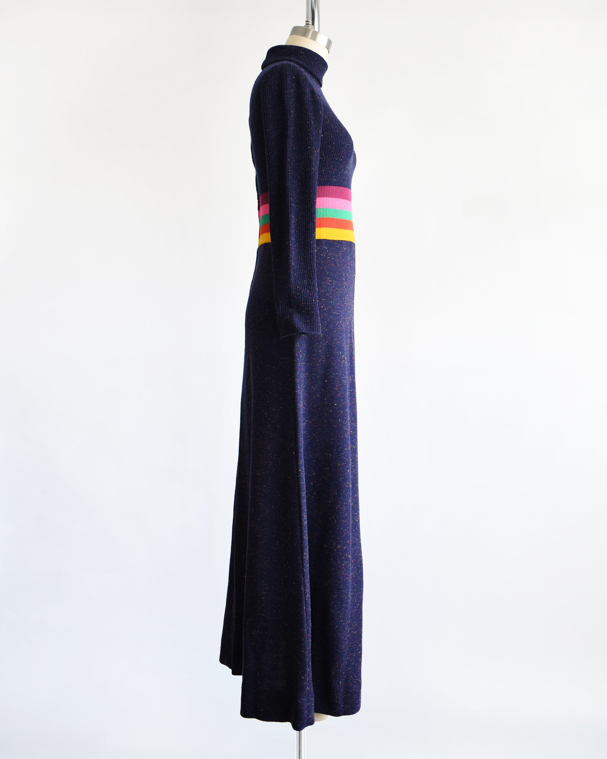 side view of a vintage 1970s purple blue dress with a colorful striped waistband on a mannequin against a white background