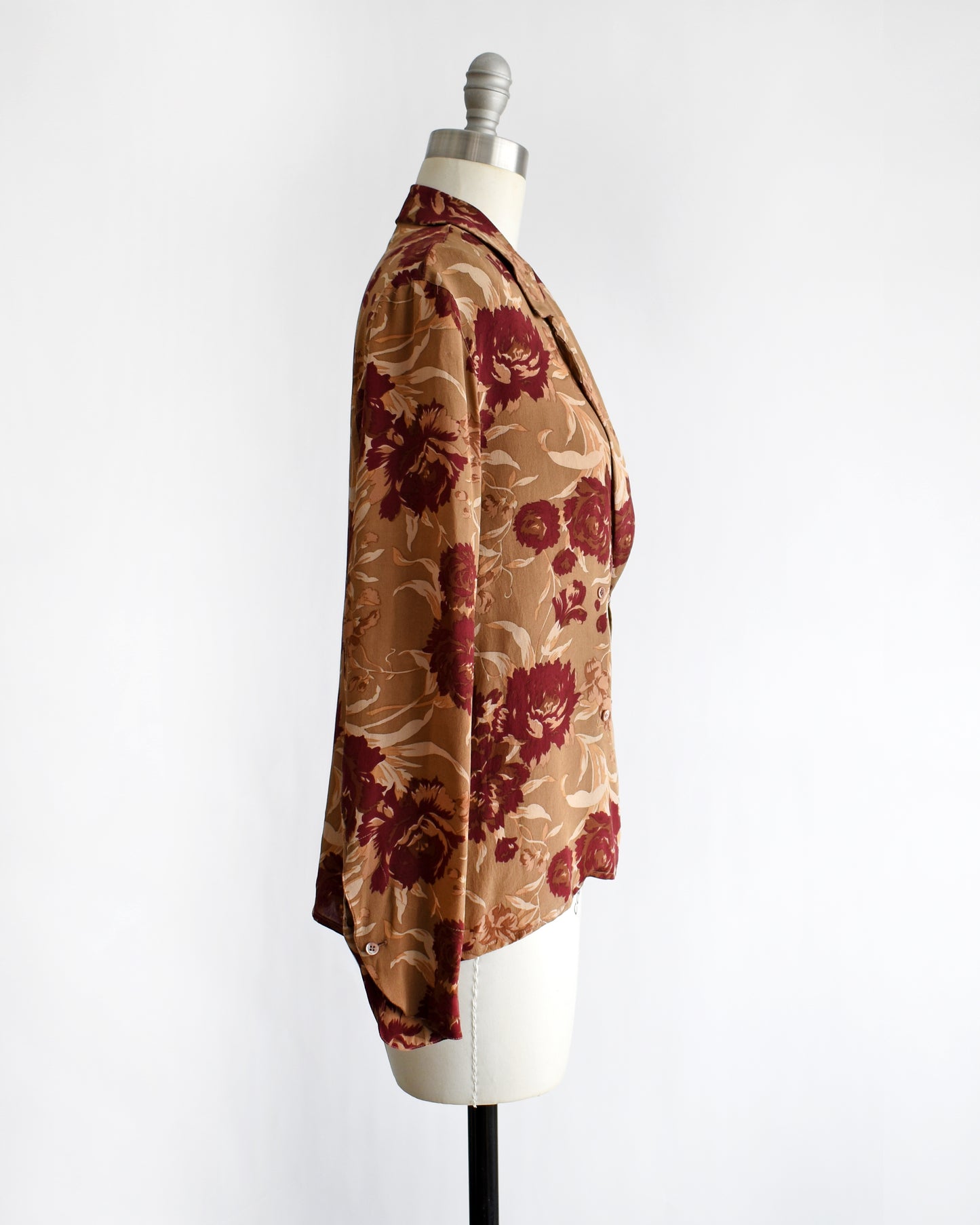 side view of a vintage floral patterned silk blouse on a mannequin against a white background