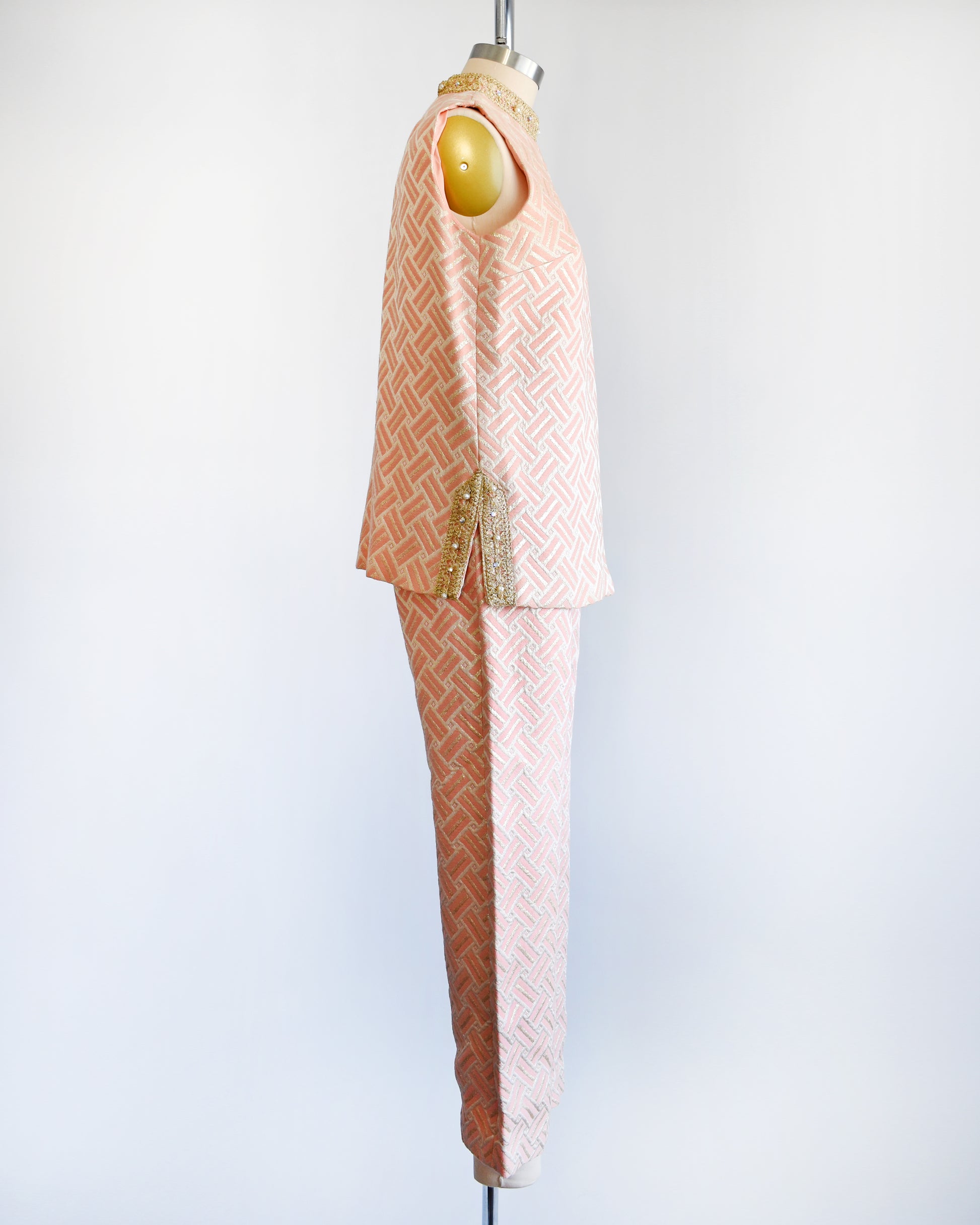 Side view of a vintage 1960s pink and gold mod pant set with a metallic gold collar with rhinestone trim. The set includes a matching top with metallic gold trim on the side