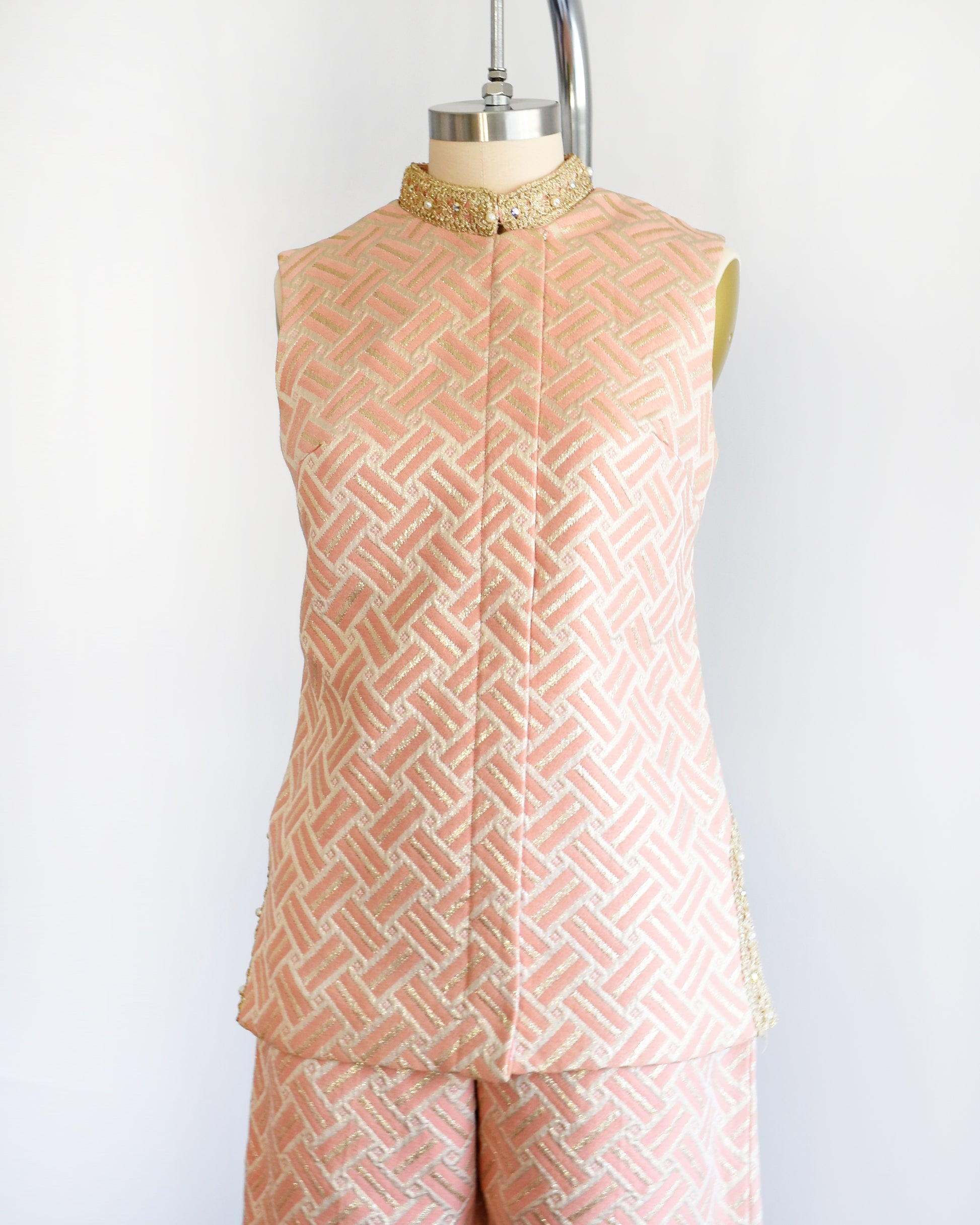 Side front view of a vintage 1960s pink and gold mod pant set with a metallic gold collar with rhinestone trim.