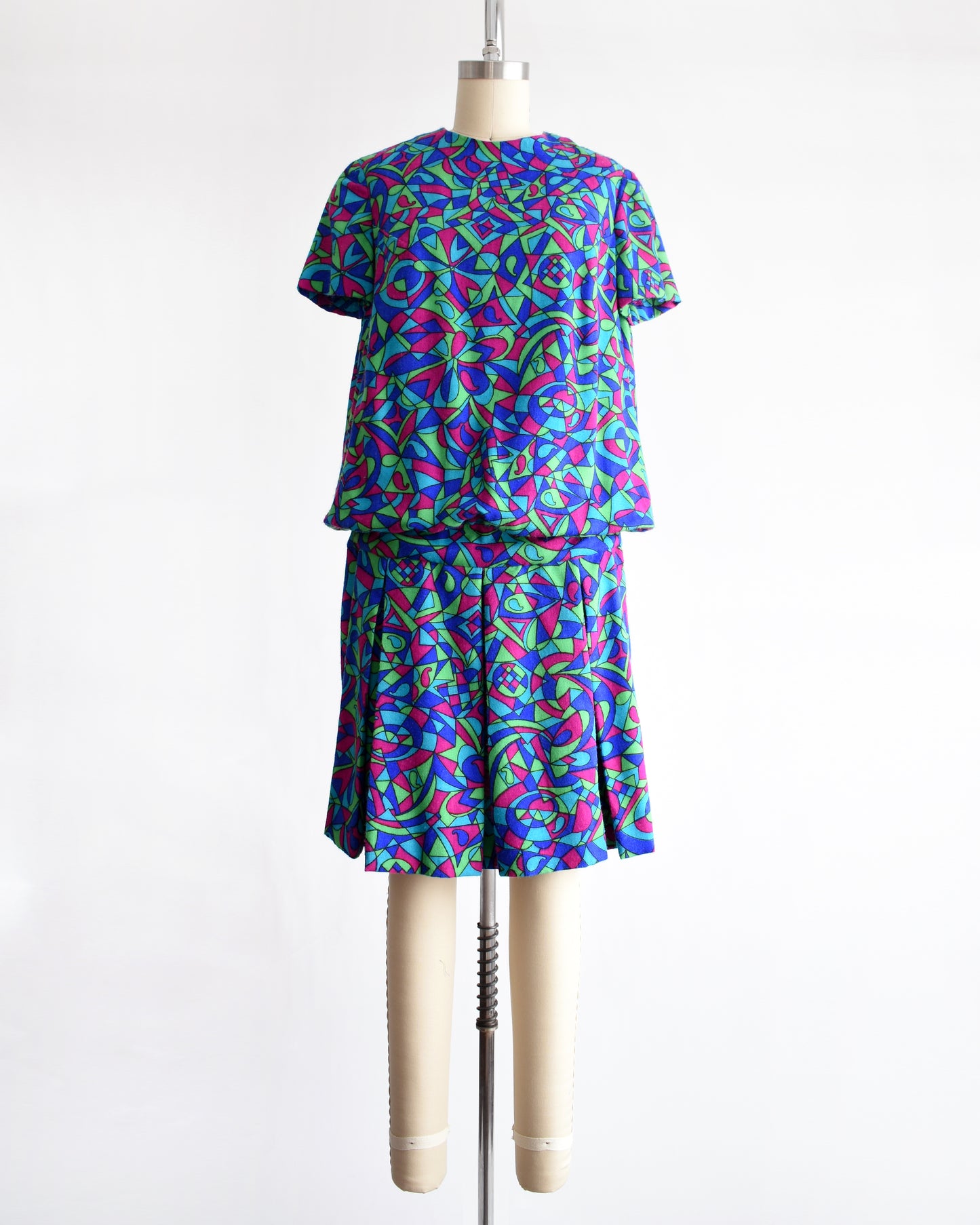 a vintage 1960s psychedelic patterned dress on a mannequin against a white background