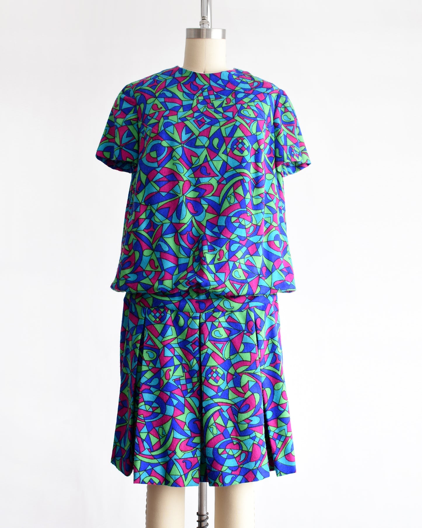 a vintage 1960s psychedelic patterned dress on a mannequin against a white background