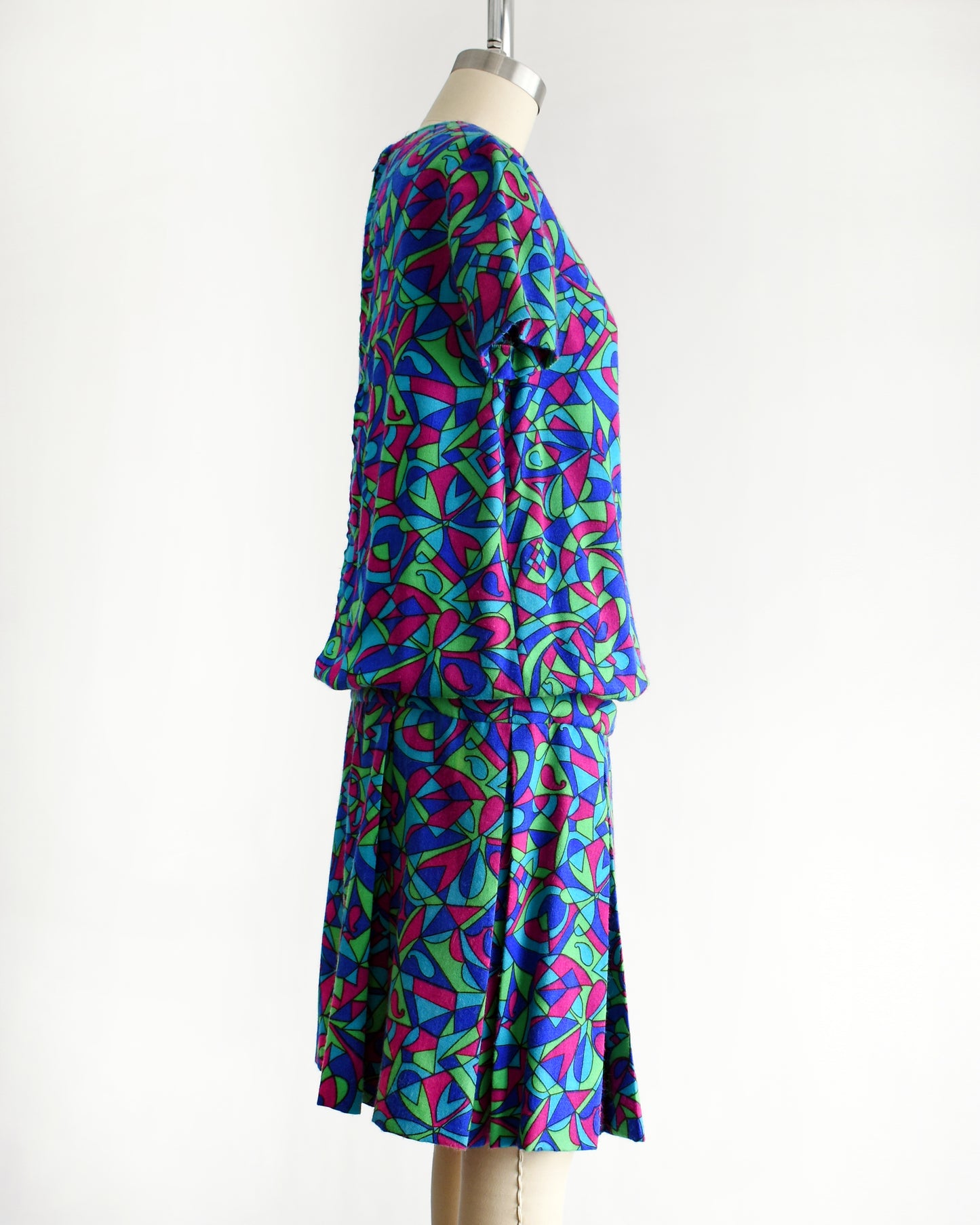 side view of a vintage 1960s psychedelic patterned dress on a mannequin against a white background